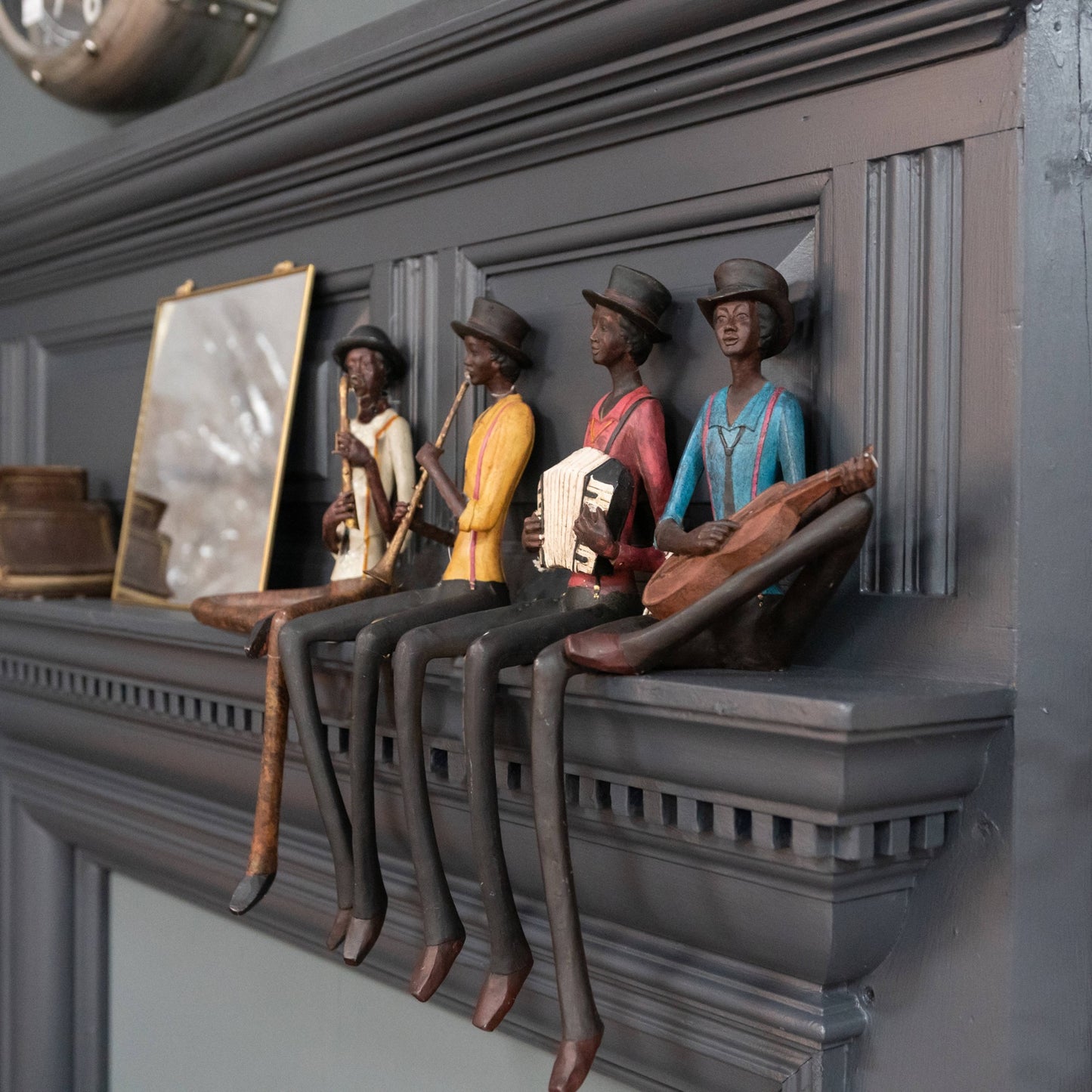 Colorful sitting jazz band figurines with elongated legs, playing instruments in a lively arrangement against a gray background.