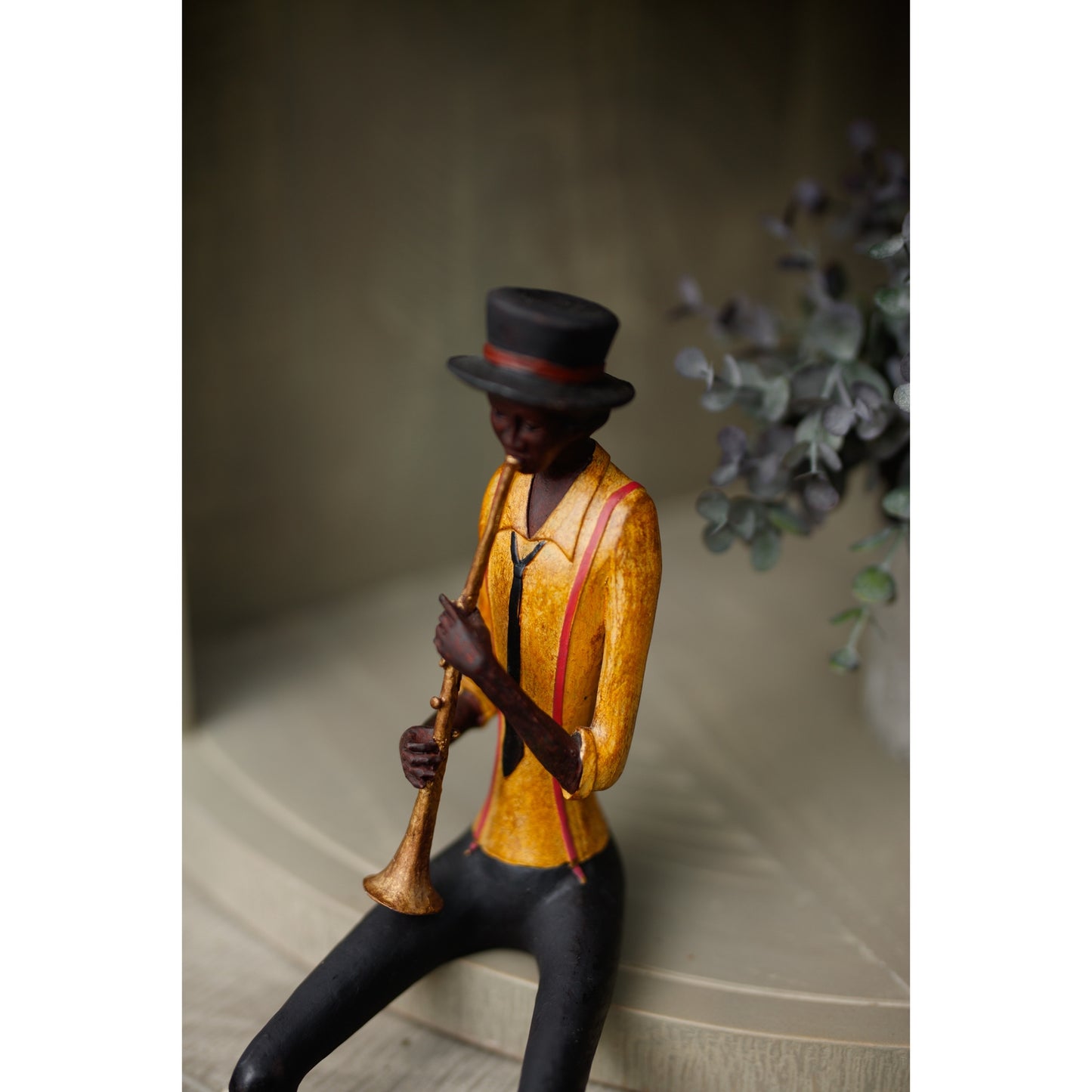Figurine of a jazz trumpeter wearing a yellow shirt and black hat, intricately detailed with a vintage aesthetic.