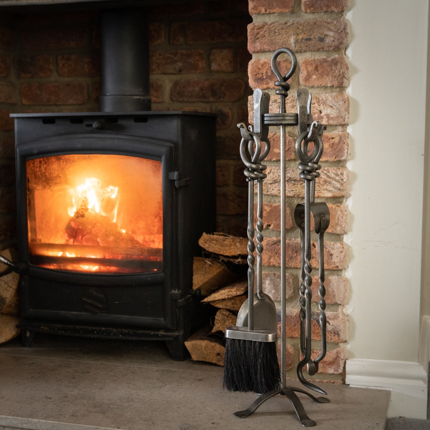 Handcrafted companion set with a sleek pewter finish and distinctive loop-top design, enhancing any fireplace setting.