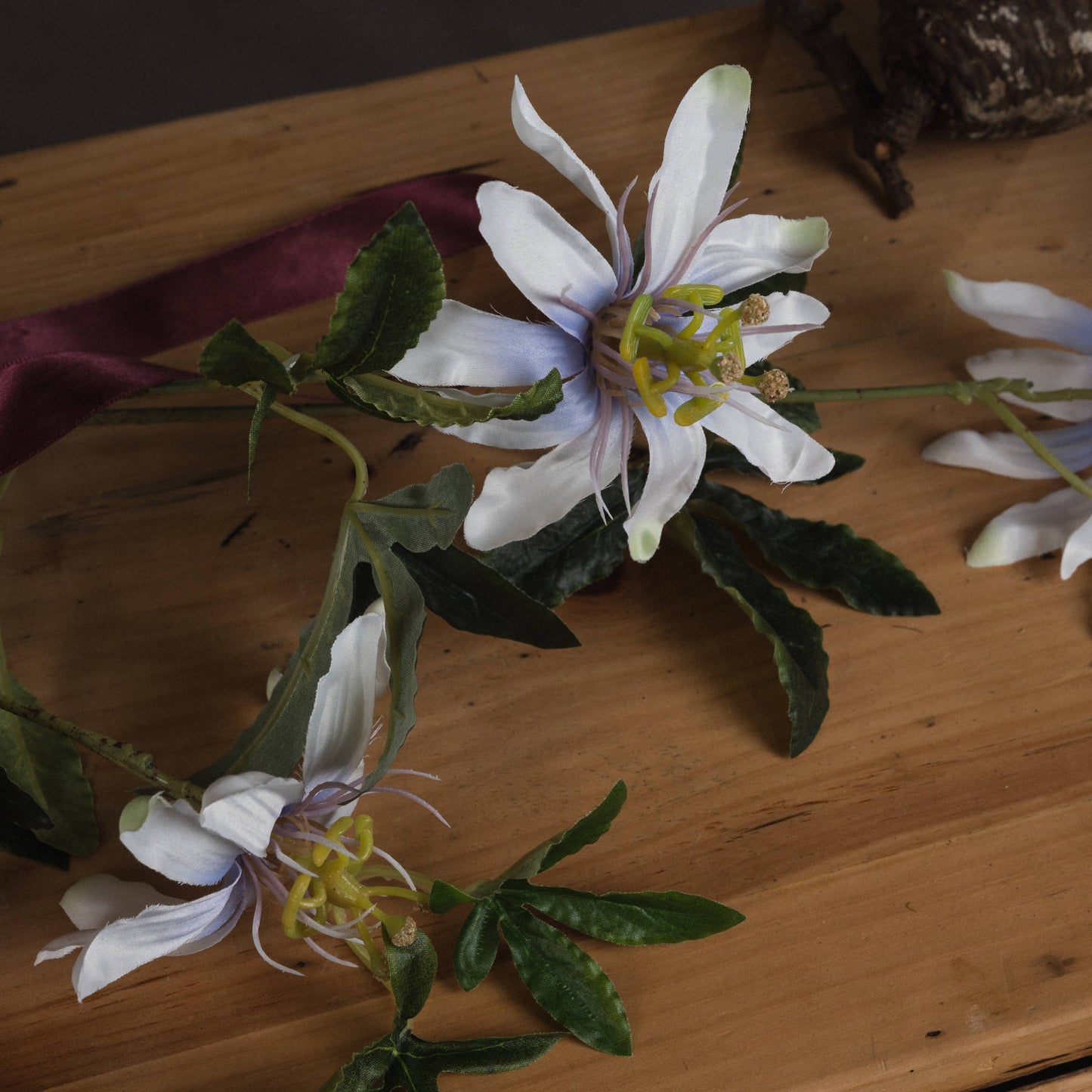 Lifelike white passion flower spray with delicate petals, fine filaments, and lush green leaves, ideal for elegant decor.