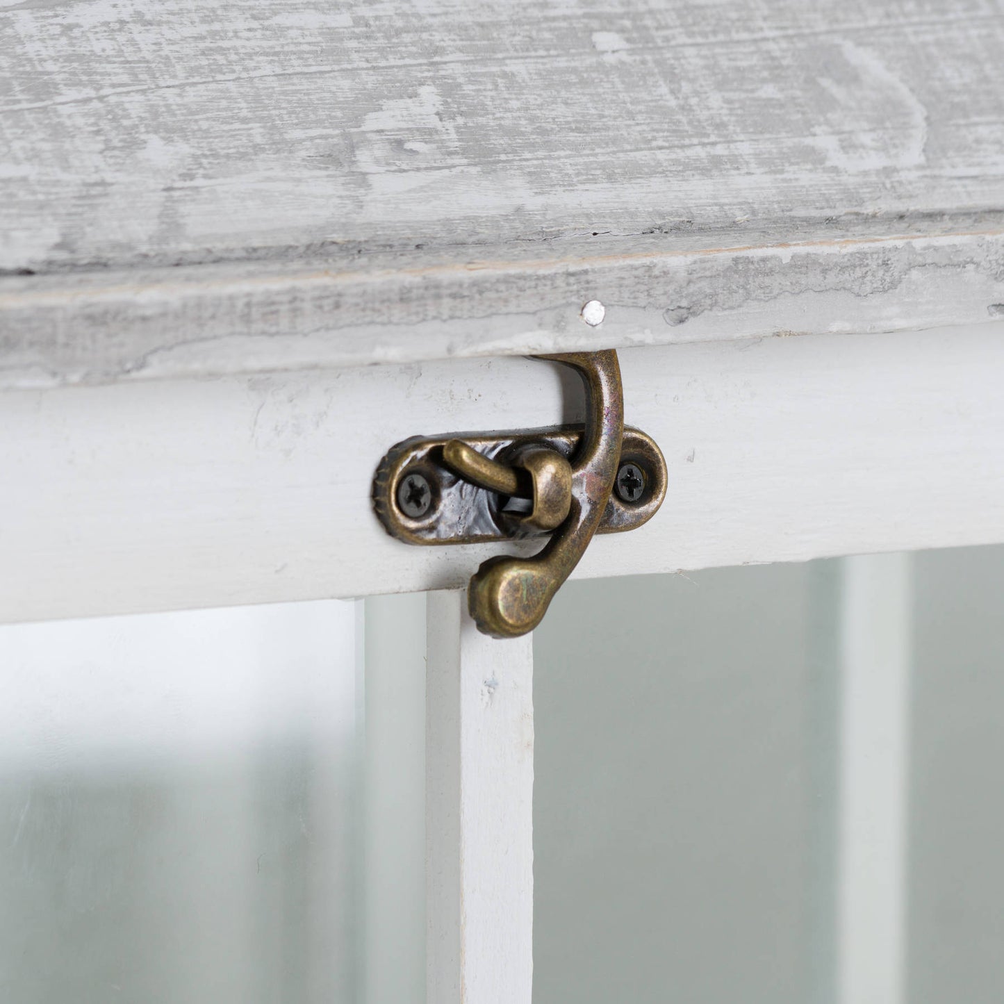 Close-up of a white lantern latch with a brass handle, showcasing intricate detailing and a rustic aesthetic.