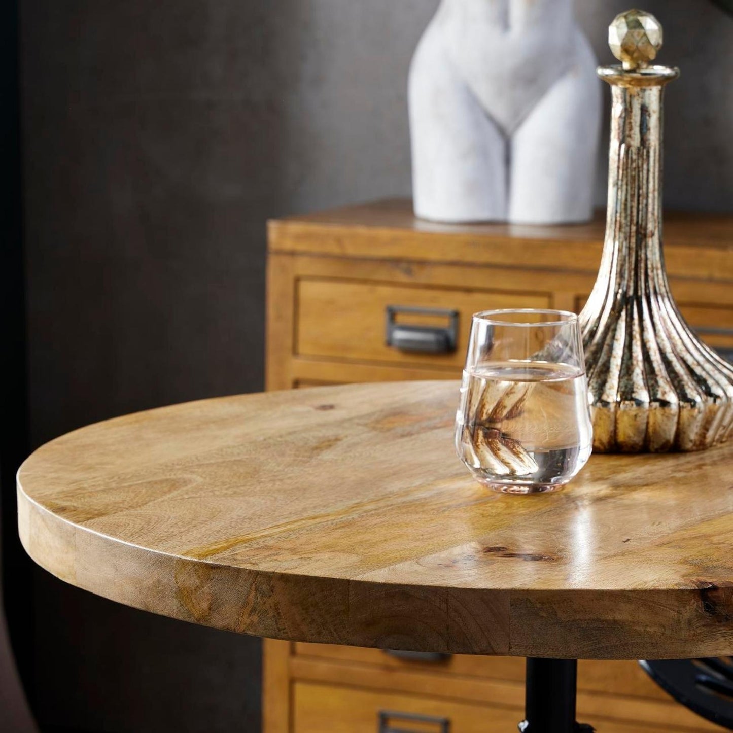 Adjustable red bistro table with a rustic weathered wood top, sturdy metal base, and a glass of water on its surface.
