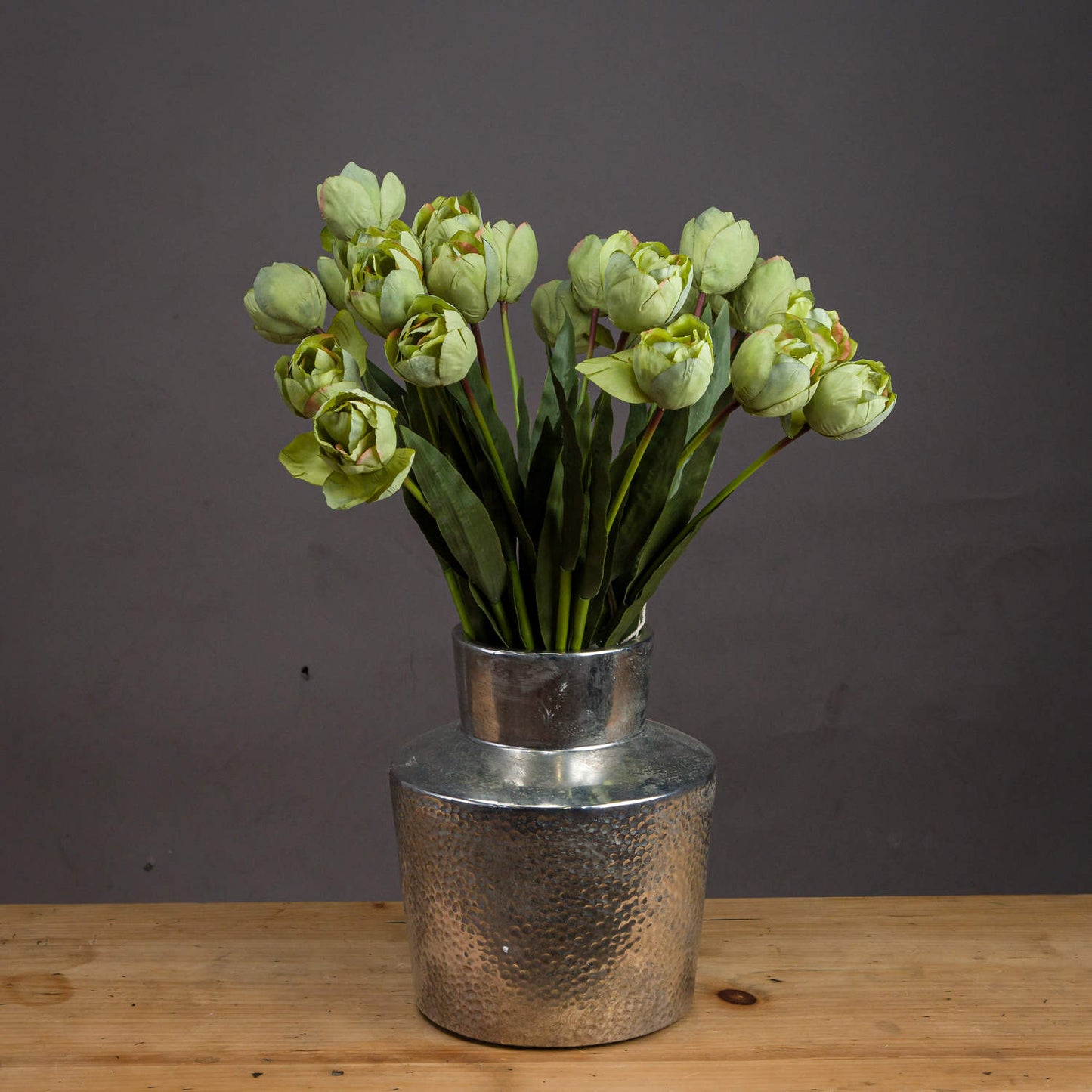 Lifelike green tulips arranged in a silver vase, showcasing realistic petals and lush leaves against a neutral backdrop.