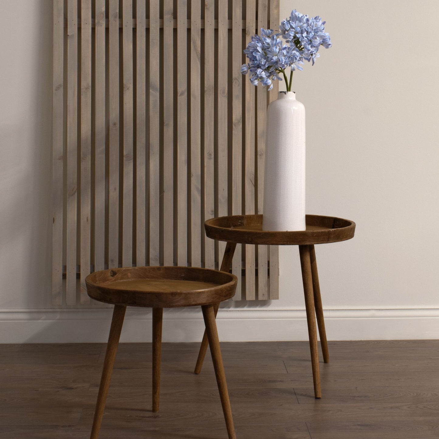 Light blue large-headed agapanthus stems in a sleek white vase on a wooden table, enhancing coastal elegance in a minimalist setting.