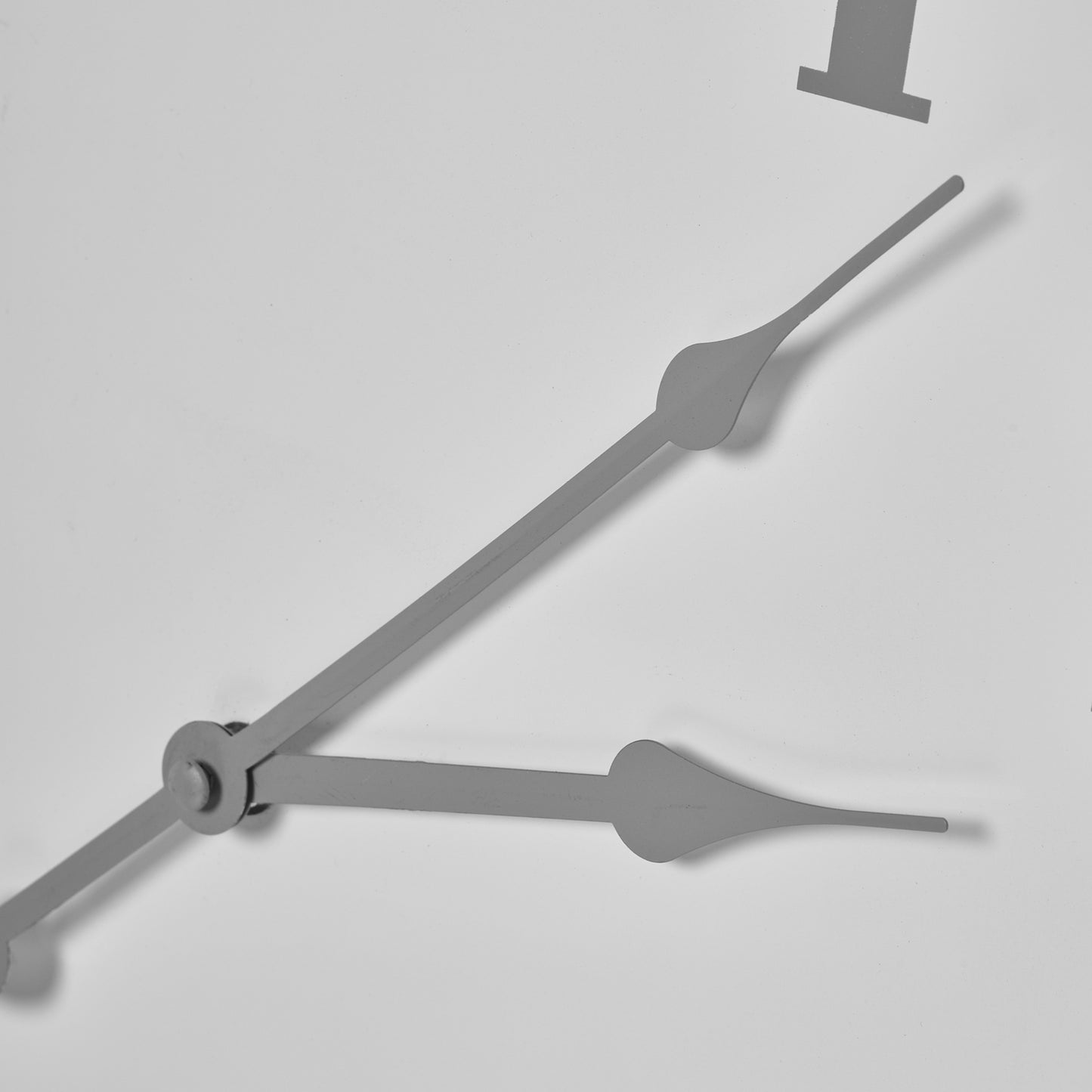 White wall clock featuring an imposing circular design with sleek metal hands, ideal for modern minimalist spaces.