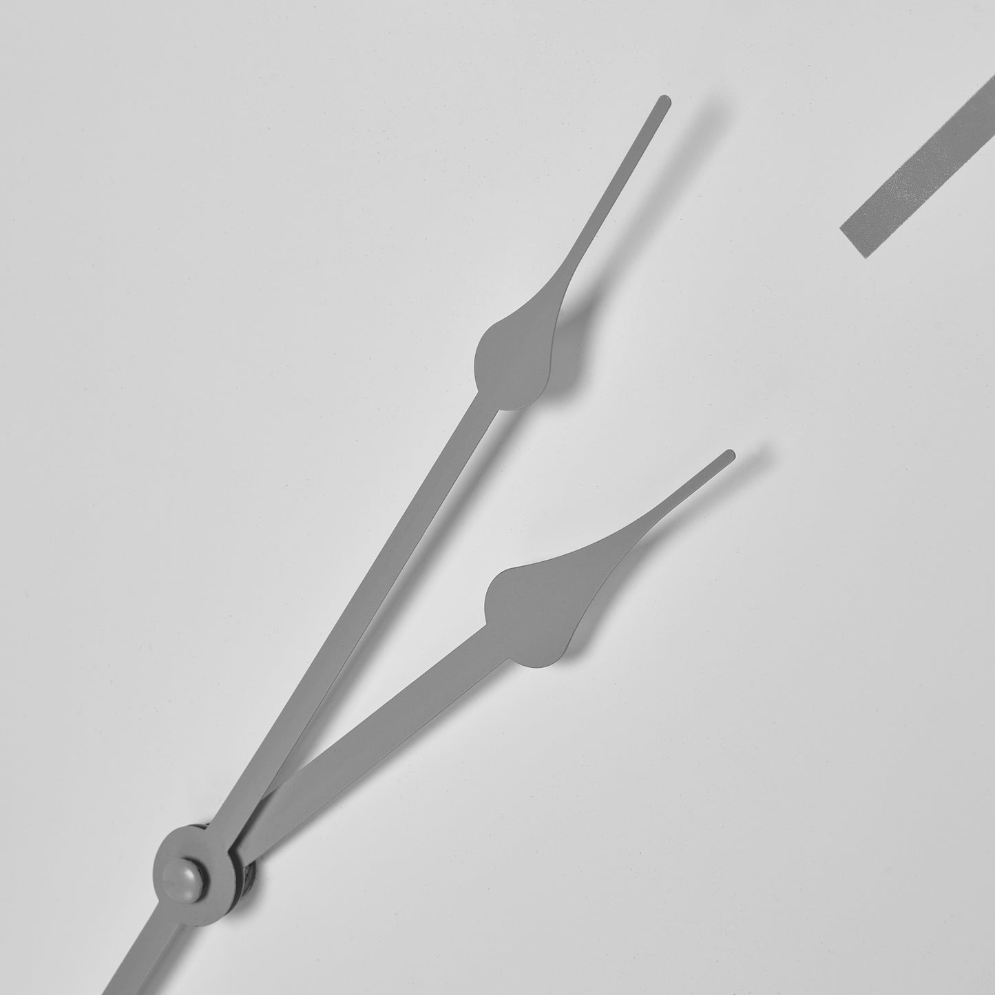 White wall clock featuring sleek gray hour and minute hands, embodying minimalist elegance and industrial chic design.