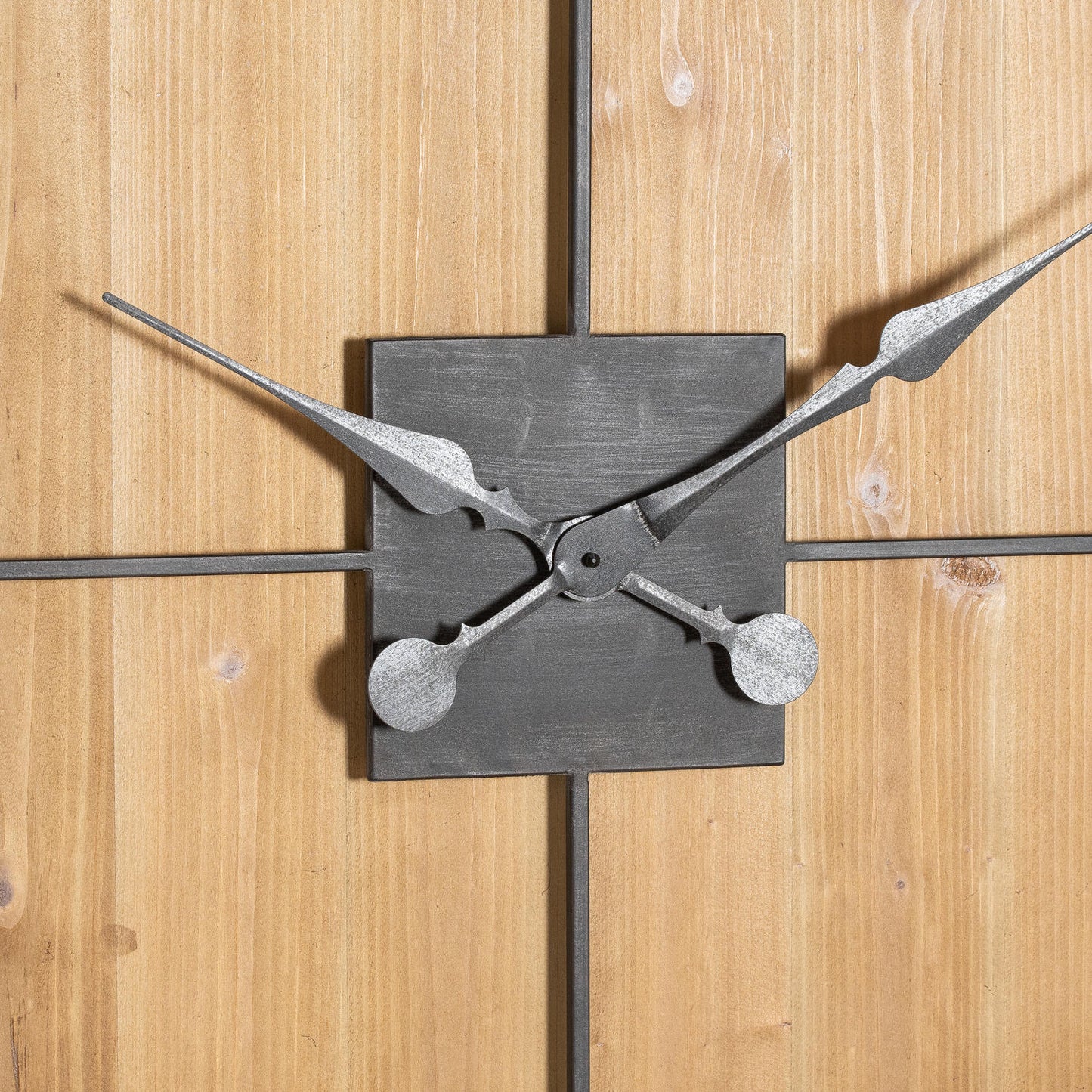 Large wooden wall clock with layered grey metal Roman numerals and black hands, set against a warm natural wood backdrop.