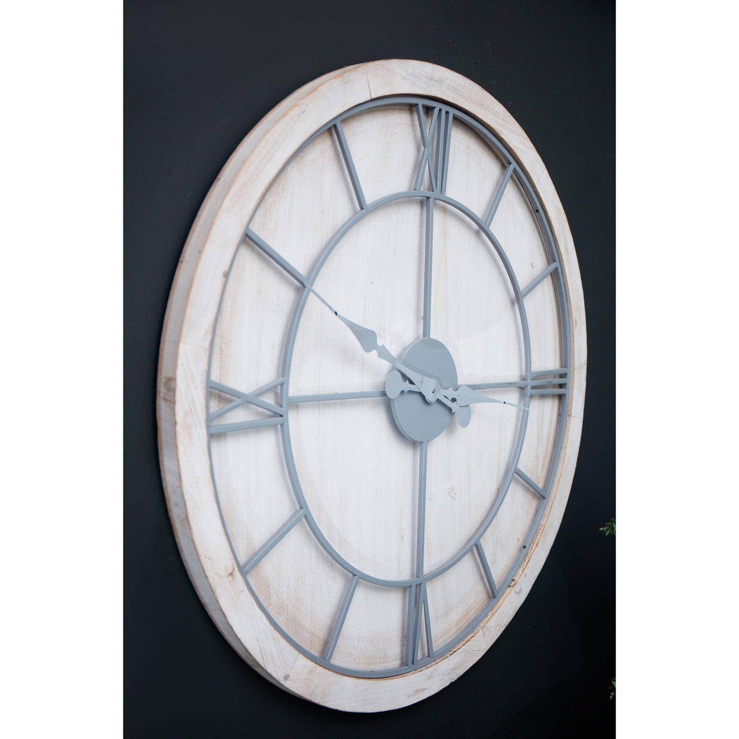 Large round wall clock with a whitewashed wood frame, light grey Roman numerals, and hands for easy readability.