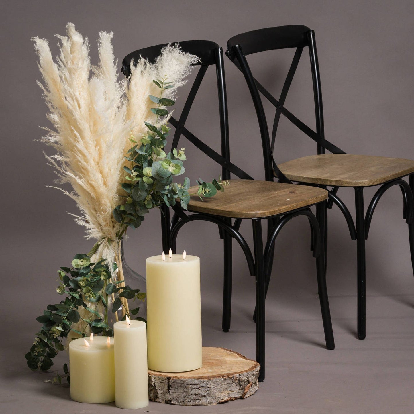 Cream pampas grass stem with feathery plumes arranged with green eucalyptus and candles, set against a neutral backdrop.