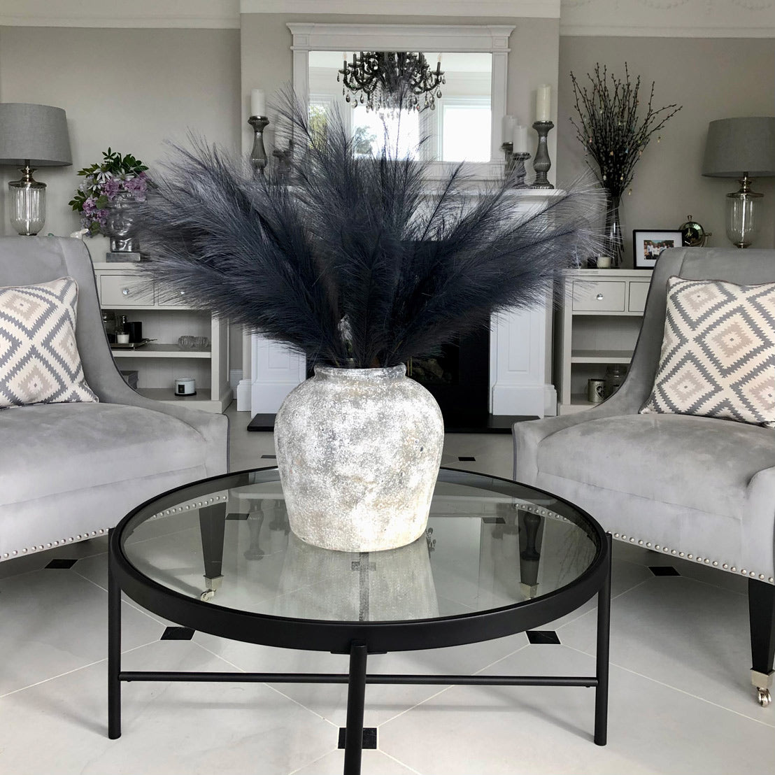 Large grey faux pampas grass stems in a textured vase, enhancing a modern living space with elegant, minimalistic appeal.