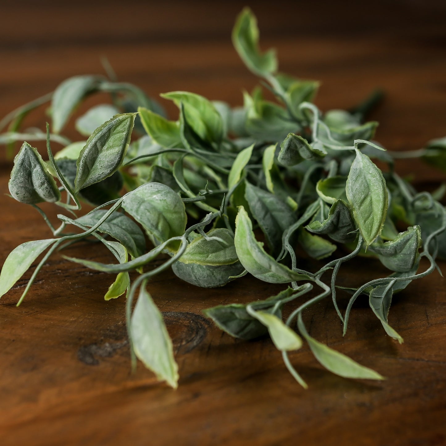 Lifelike green foliage with varied shades and organic movement, resting on a wooden surface, perfect for home decor.