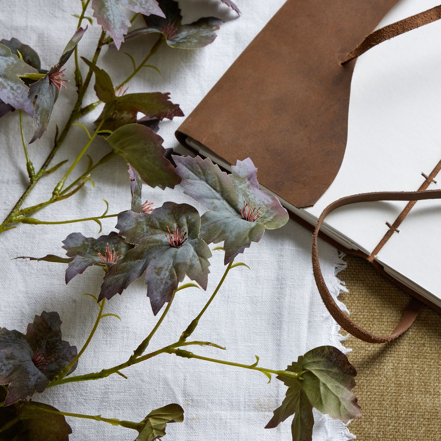 Variegated maple leaf stem featuring rich amber and deep burgundy hues, complemented by delicate veining and greenery.