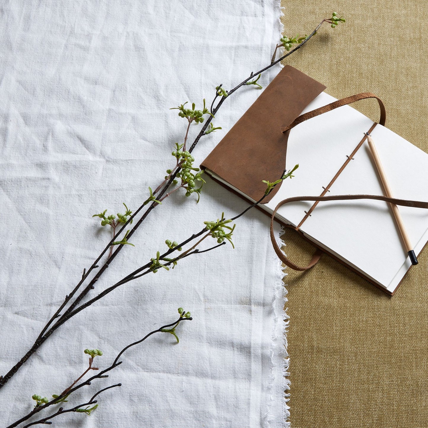 Green Berry Willow Stem featuring realistic green berries and slender branches, styled alongside a brown notebook and pencil.