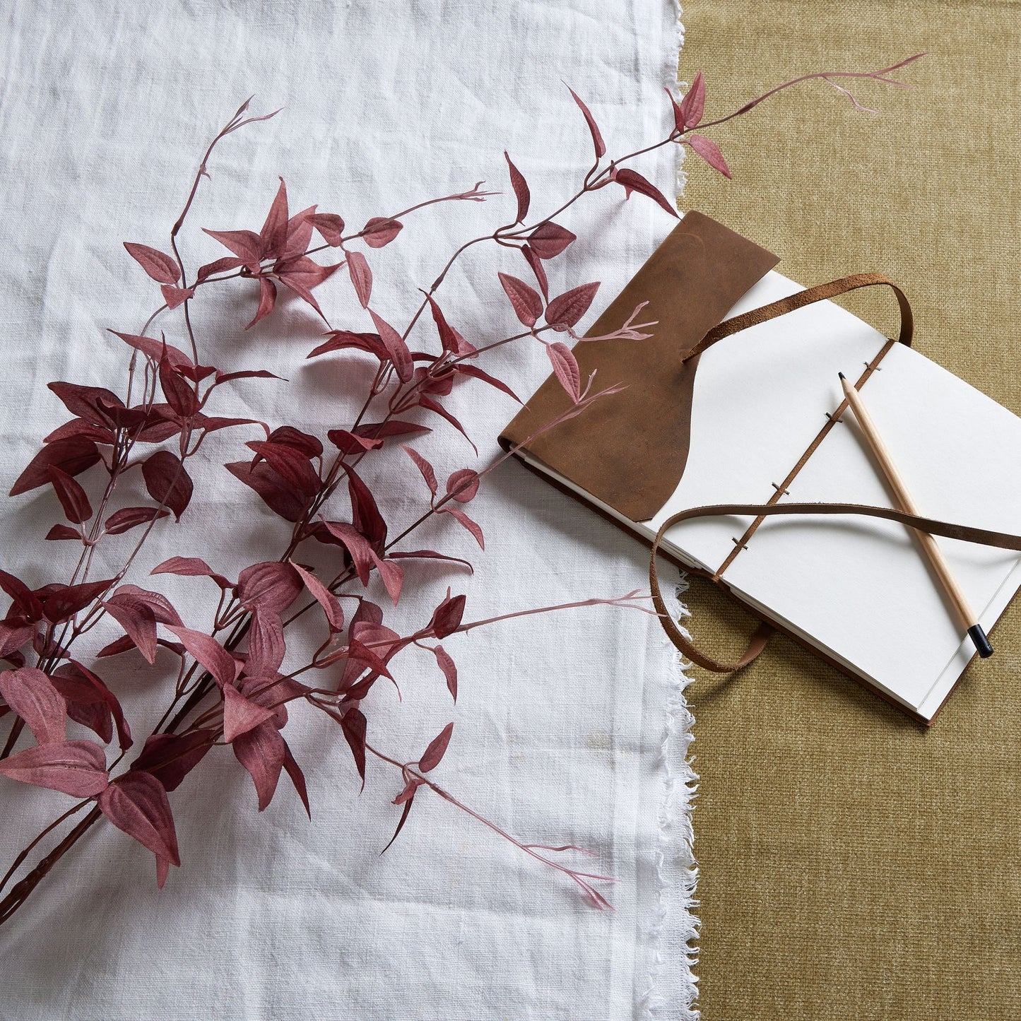 Rich burgundy leaves with delicate tendrils, elegantly arranged on textured fabrics. Ideal for autumn decor and year-round charm.
