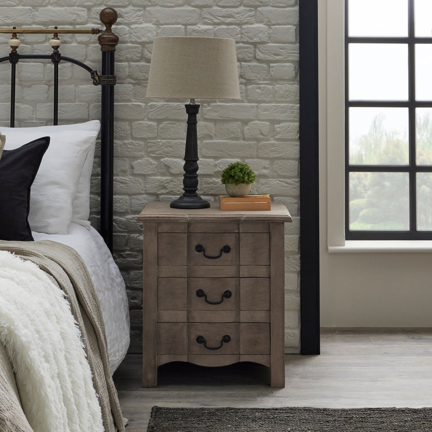 Red bedside table with three drawers, black iron handles, and a washed, bleached wood finish, styled in a classic French design.