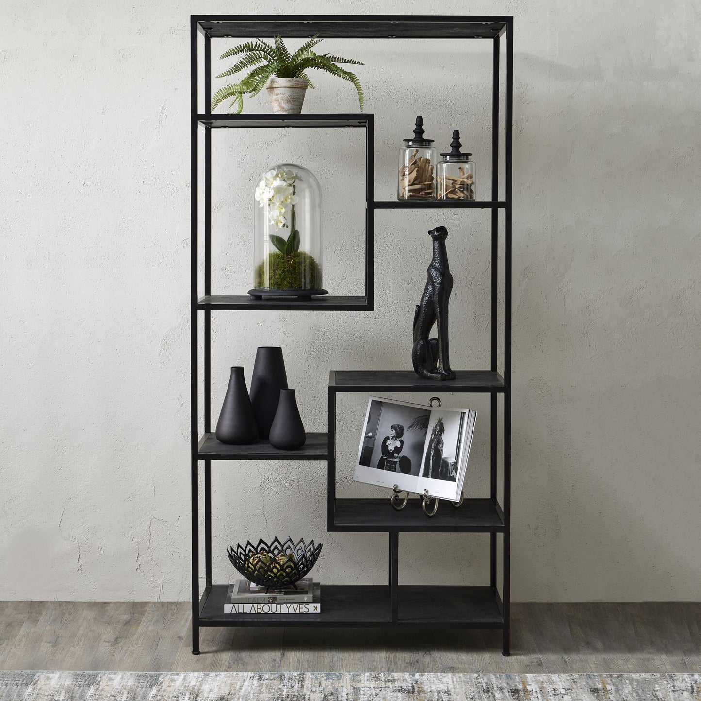 Large black multi-shelf unit with asymmetrical design, featuring staggered shelves, intricate metalwork, and decorative items.