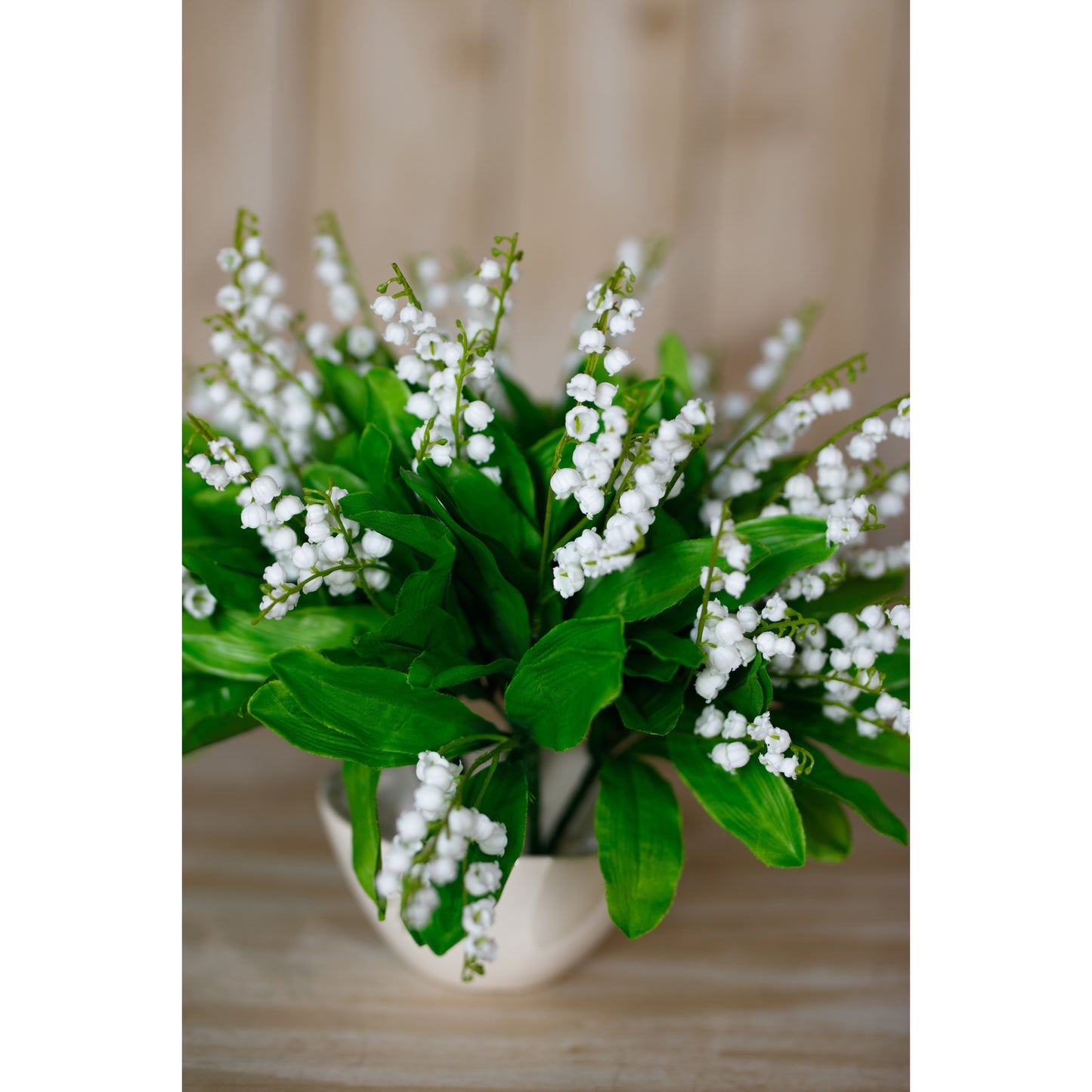 Artificial Lily of the Valley bunch features delicate white blooms and lush green leaves, elegantly arranged in a neutral pot.