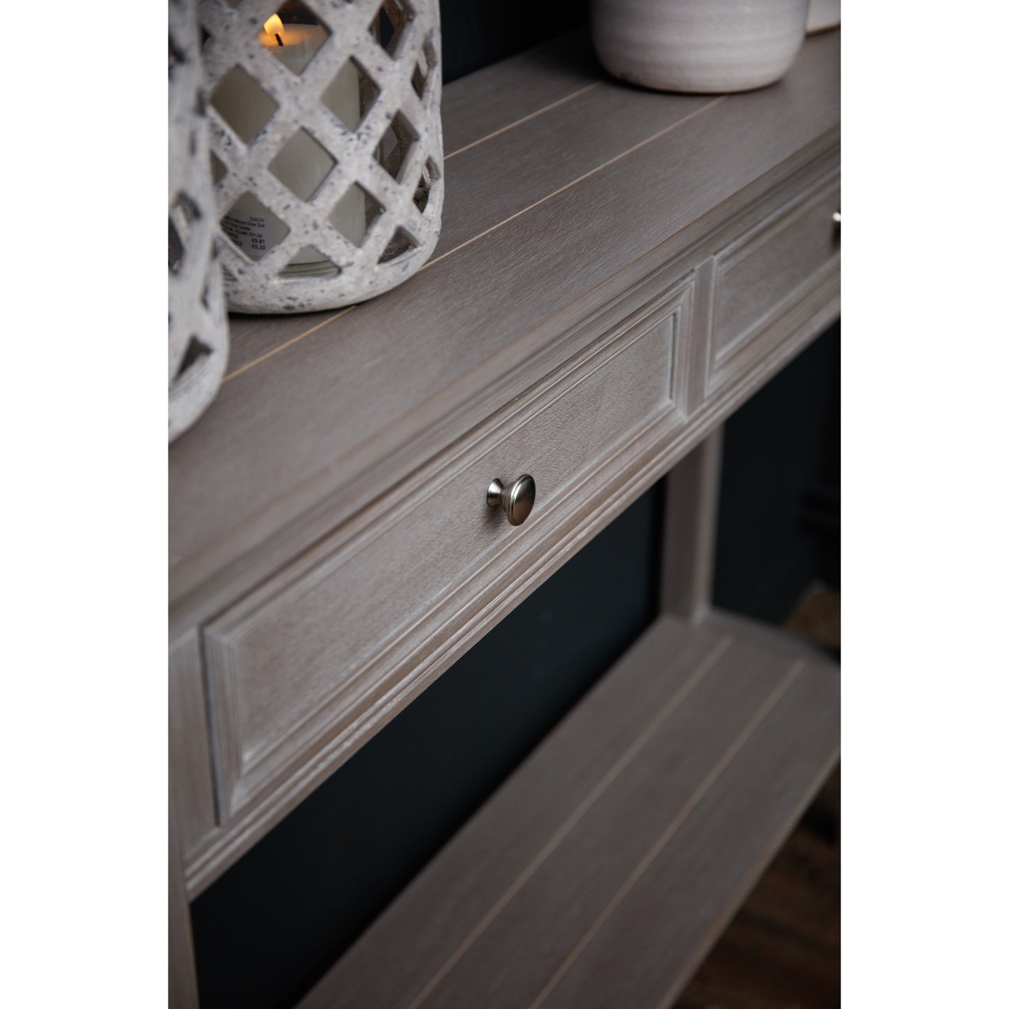 Light gray console table with two drawers, featuring a polished look, subtle detailing, and metallic knobs, set against a dark background.