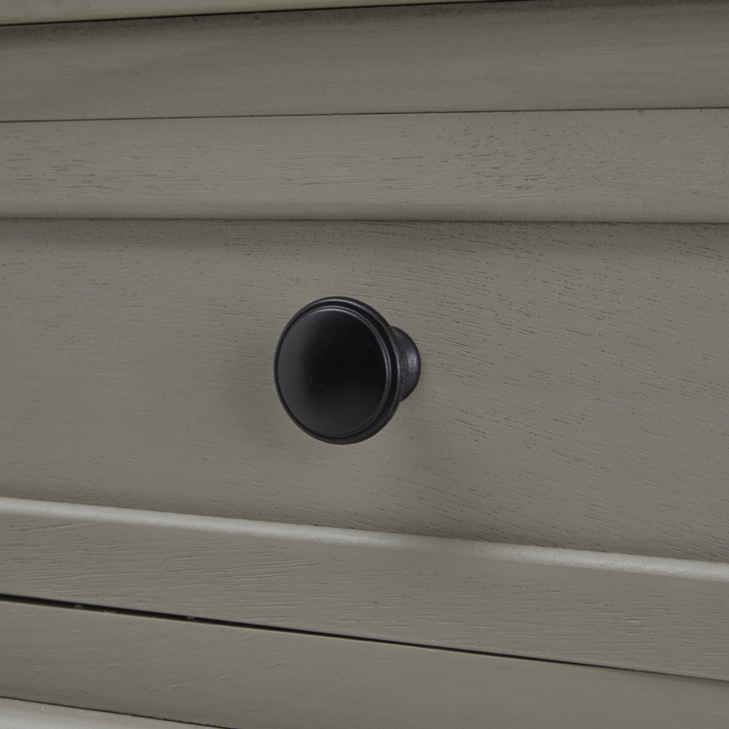 Black round knob on a grey console table drawer, showcasing elegant craftsmanship and modern British design.