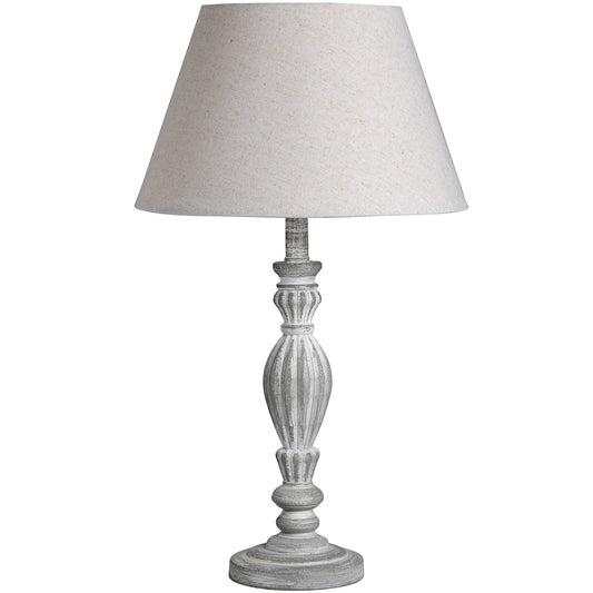 Wooden table lamp in a weathered neutral finish with graceful curves, topped by a light fabric shade, perfect for various decor styles.
