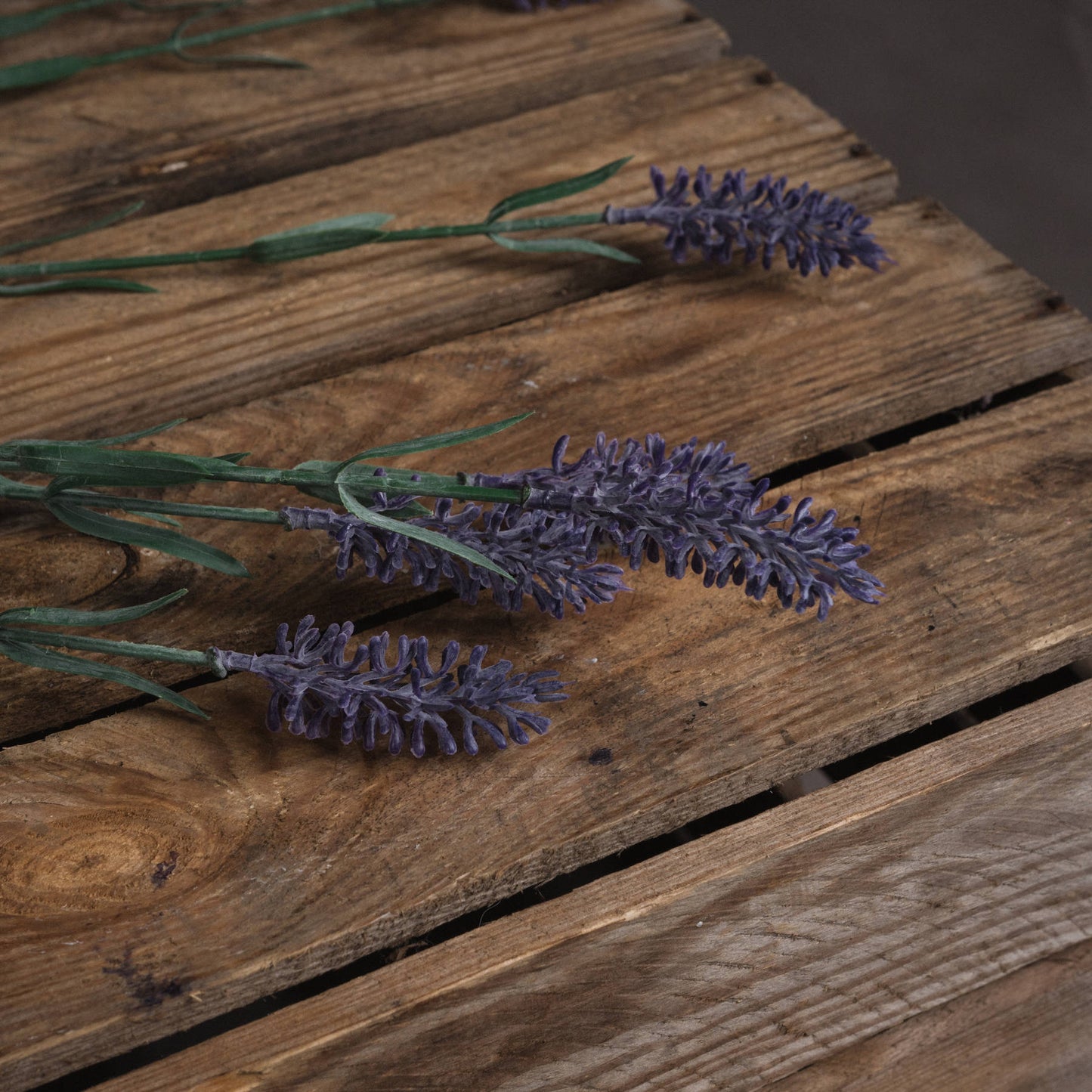Nine meticulously crafted lavender blooms in vibrant purple, arranged on a rustic wooden surface, with flexible green stems for versatile styling.