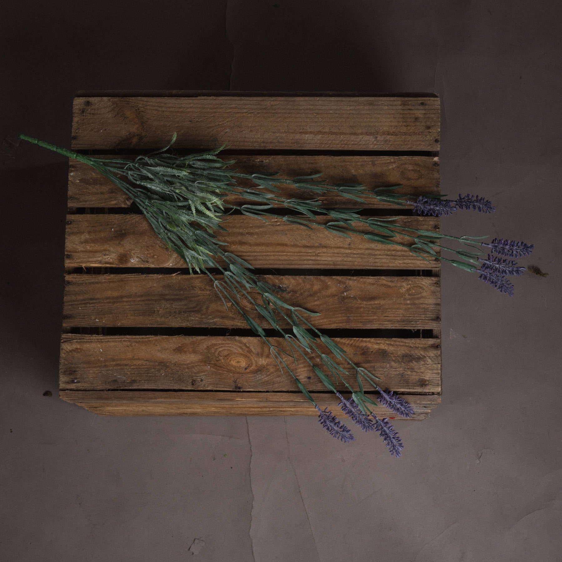 Large lavender spray with nine purple blooms and green foliage, elegantly arranged on a rustic wooden surface.
