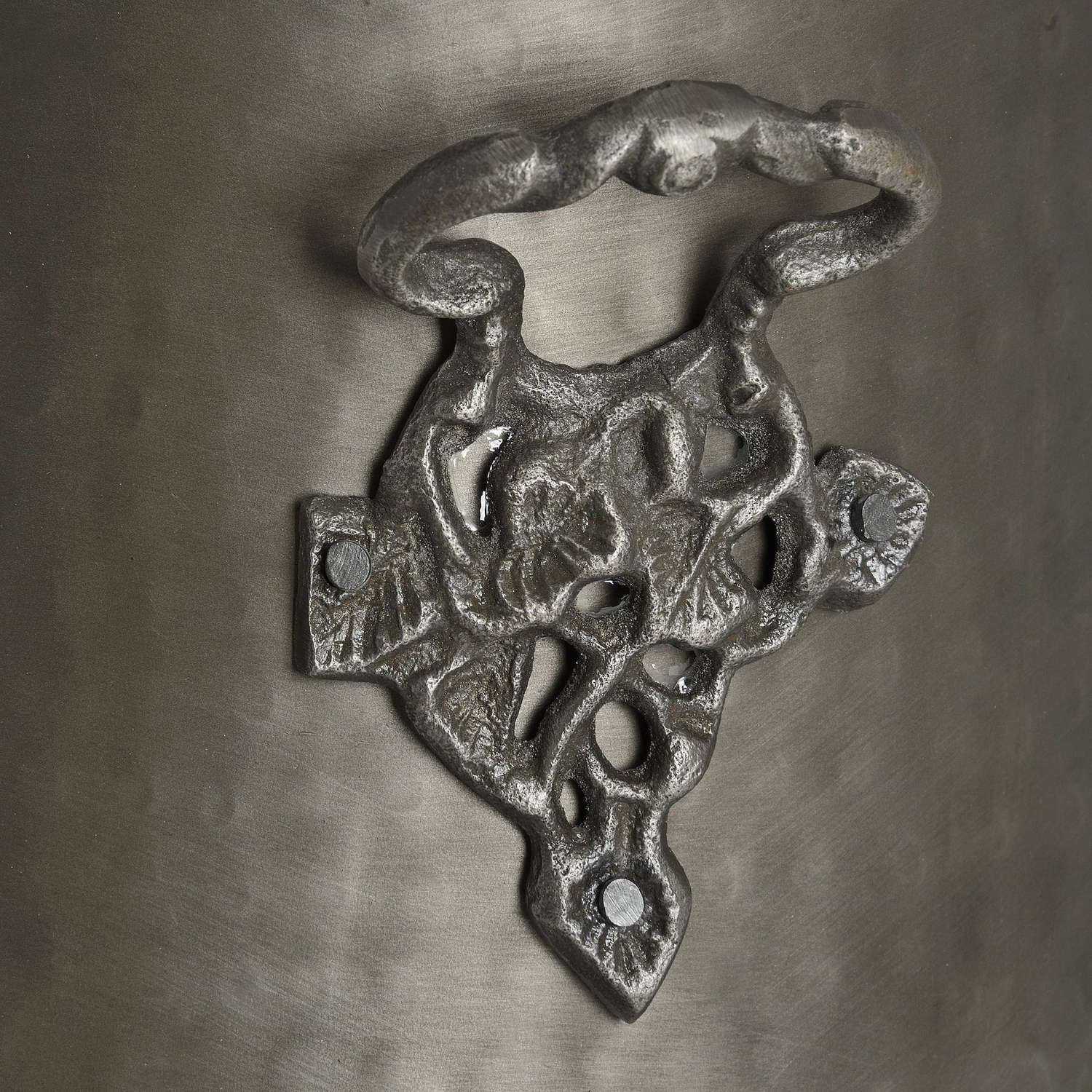 Antique pewter coal bucket featuring an ornate leaf motif handle against a rich pewter finish, exuding sophistication.