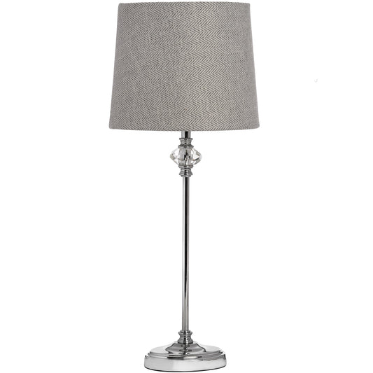 Elegant table lamp with a chrome base, hand-cut glass accent, and a grey herringbone shade, creating a warm, inviting glow.