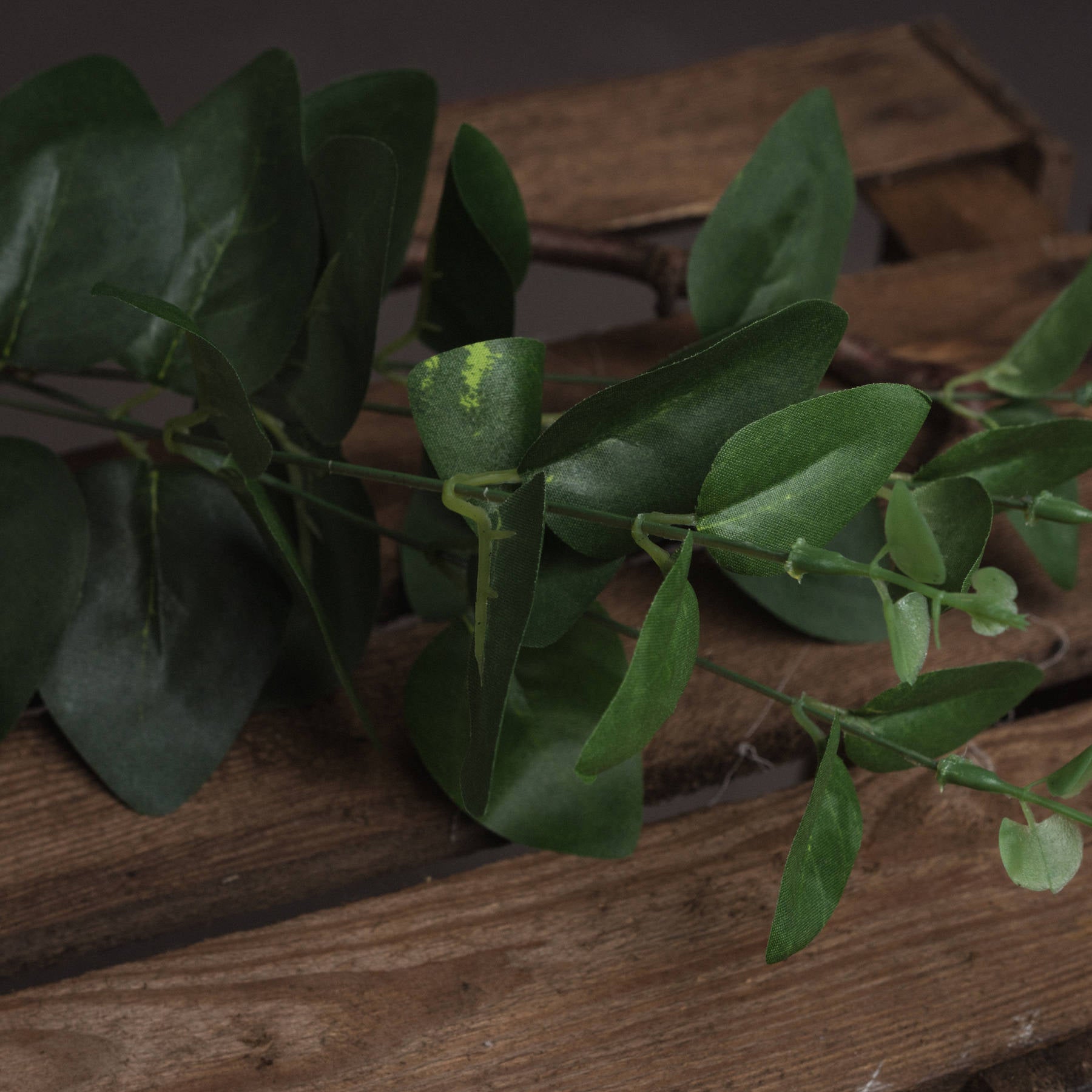 Dark green eucalyptus leaves on a short stem, showcasing lifelike foliage for elegant home decor enhancement.