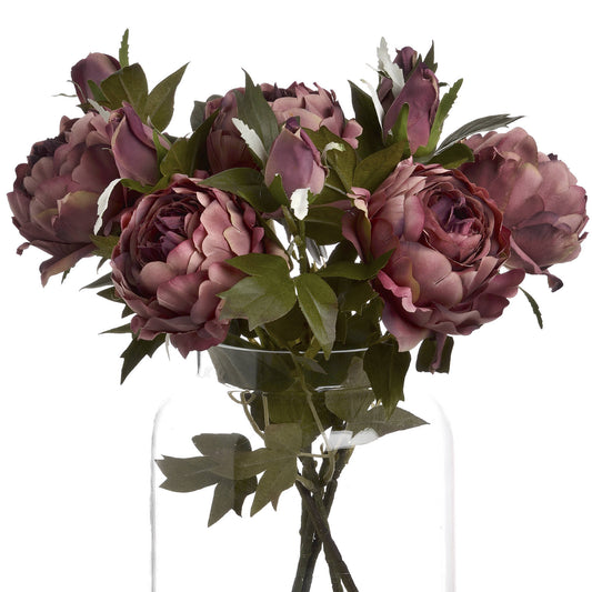 Dusty pink spray rose peonies with lush green leaves in a clear vase, showcasing elegant blooms and buds for sophisticated decor.