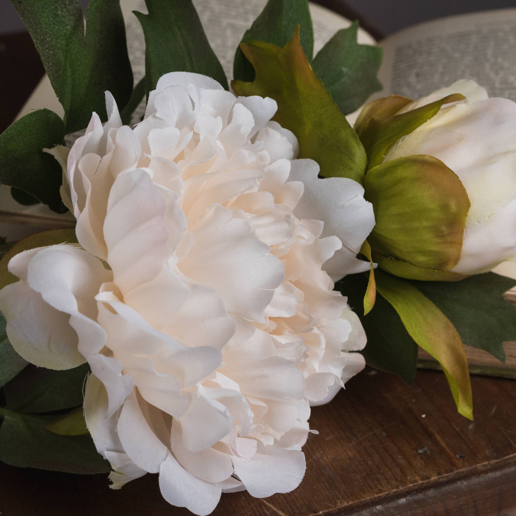 Lifelike white peony with delicate petals and lush green leaves, perfect for elegant home decor.
