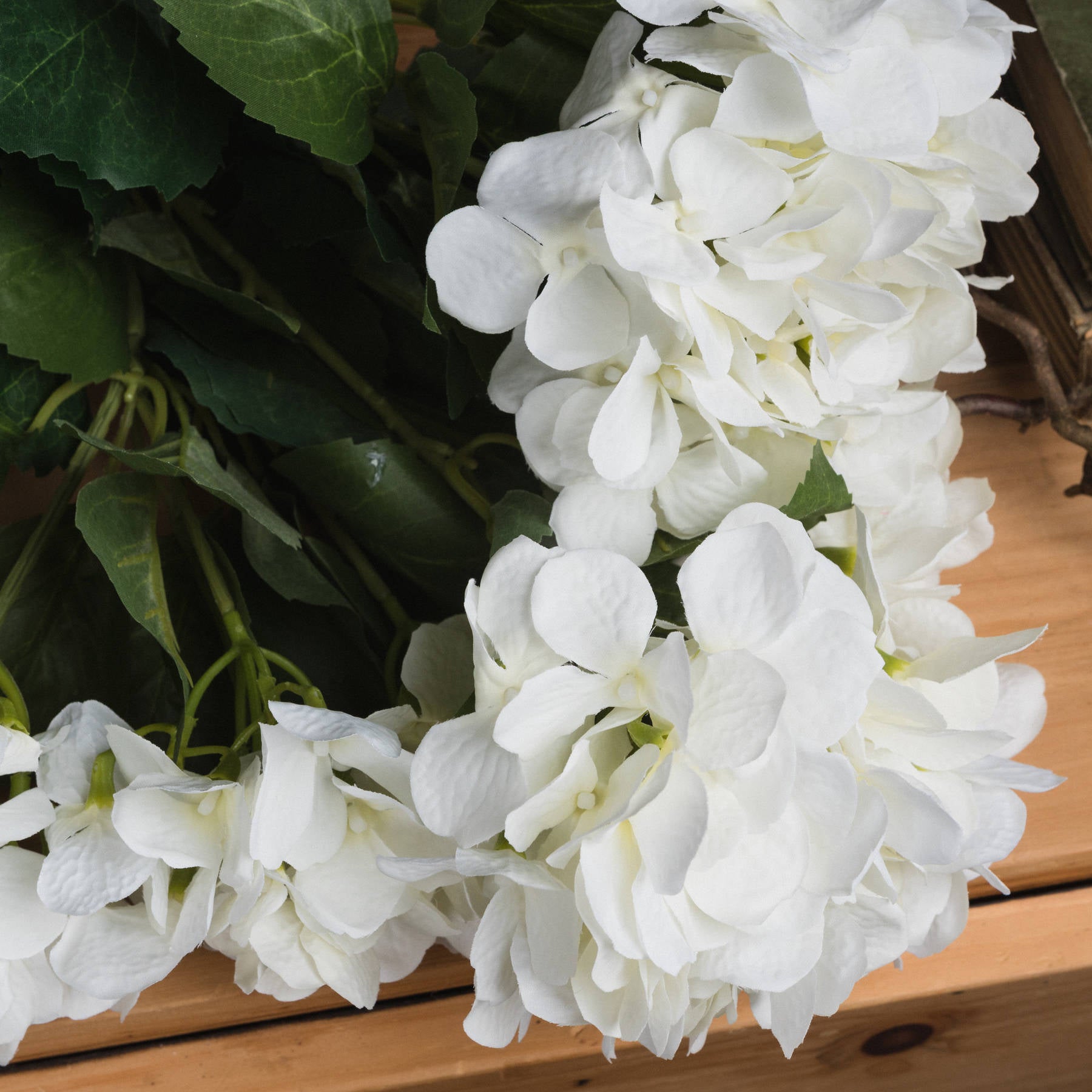 Lifelike white hydrangea bouquet with multiple bloom clusters and green foliage, enhancing home decor with elegance and versatility.