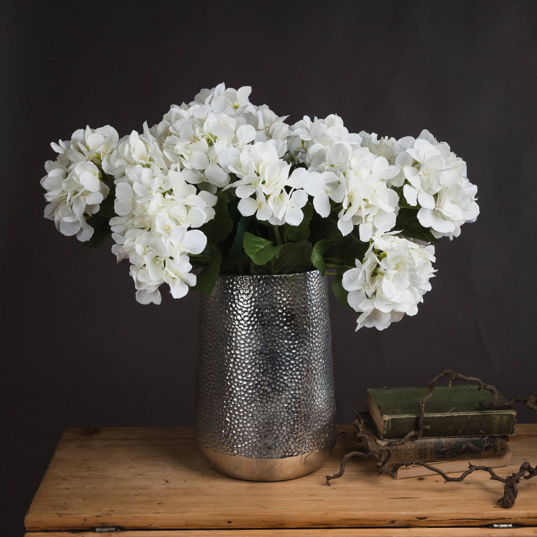 Lifelike white hydrangea bouquet in a textured silver vase, accentuating elegance and sophistication in any decor.