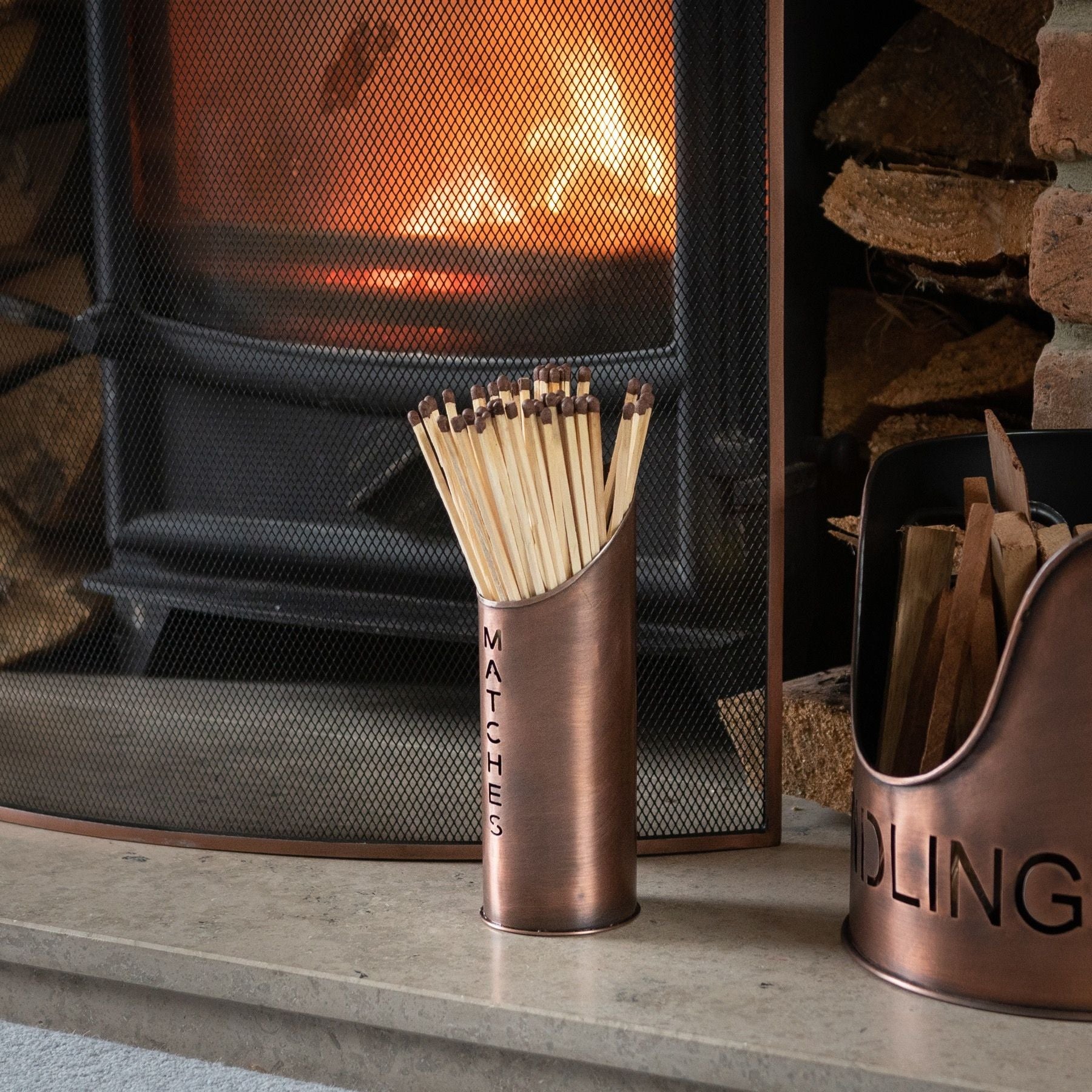 Copper-finished log and kindling buckets with a secure matchstick holder, adding elegance to the hearthside while organizing essentials.