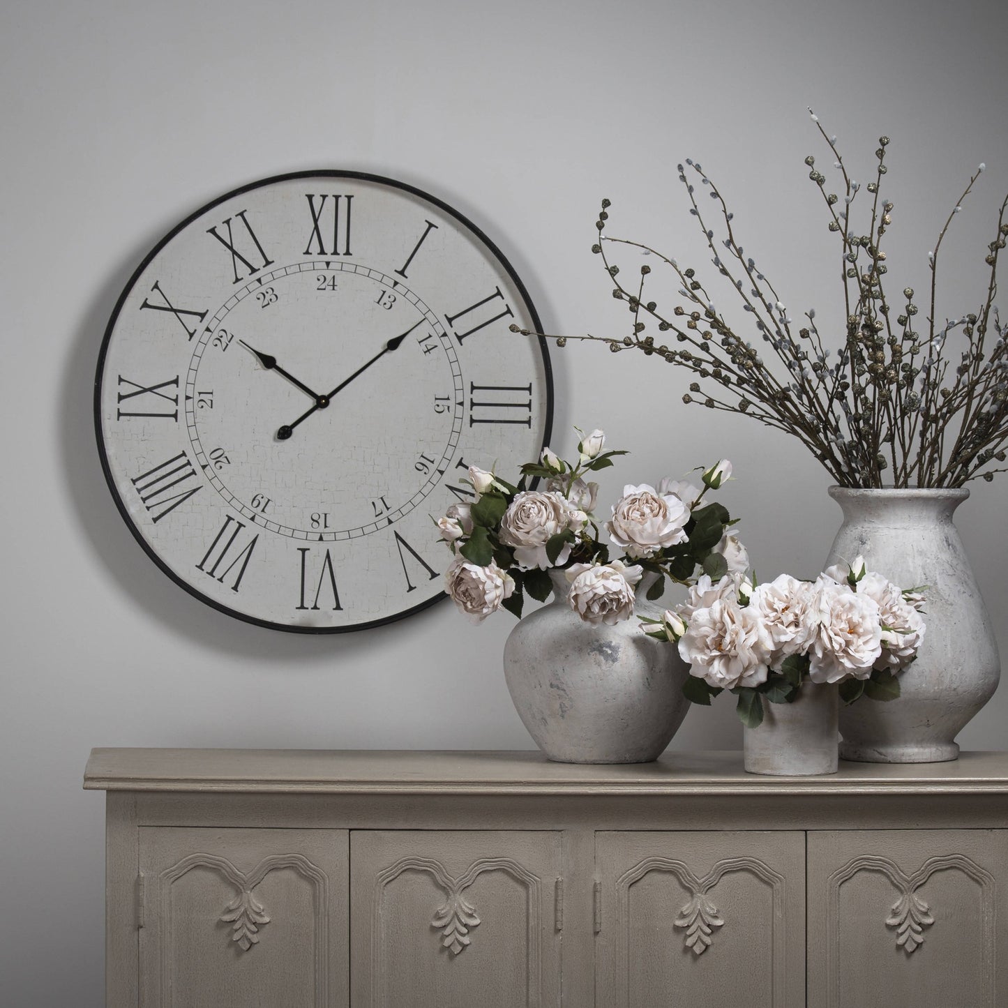 Large white embossed wall clock with Roman numerals, 80cm diameter, complemented by elegant vases and faux flowers.