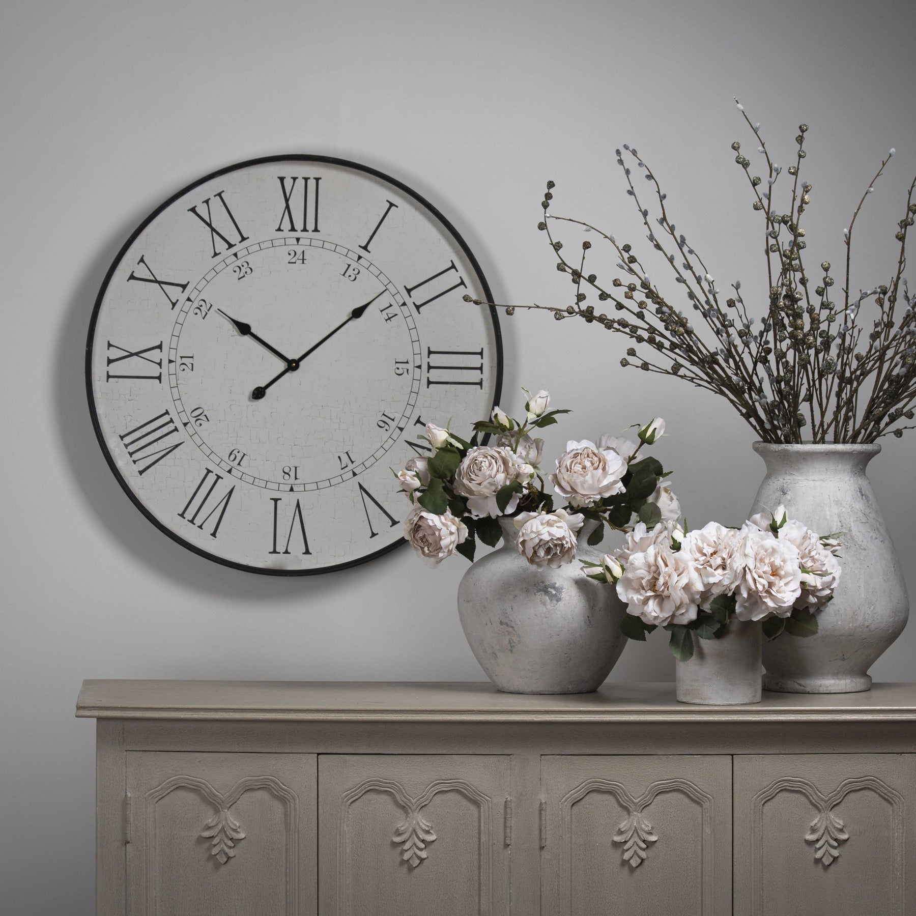 Large white embossed wall clock with Roman numerals, 80cm diameter, complemented by elegant vases and faux flowers.