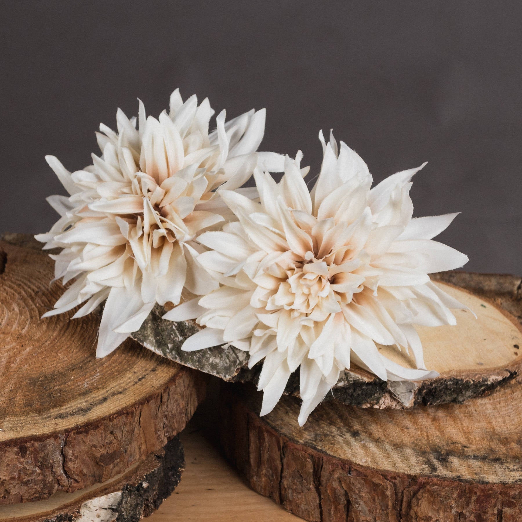 Cream dahlia artificial flowers in warm café au lait tones, displayed on wooden slices, enhancing elegant home decor.