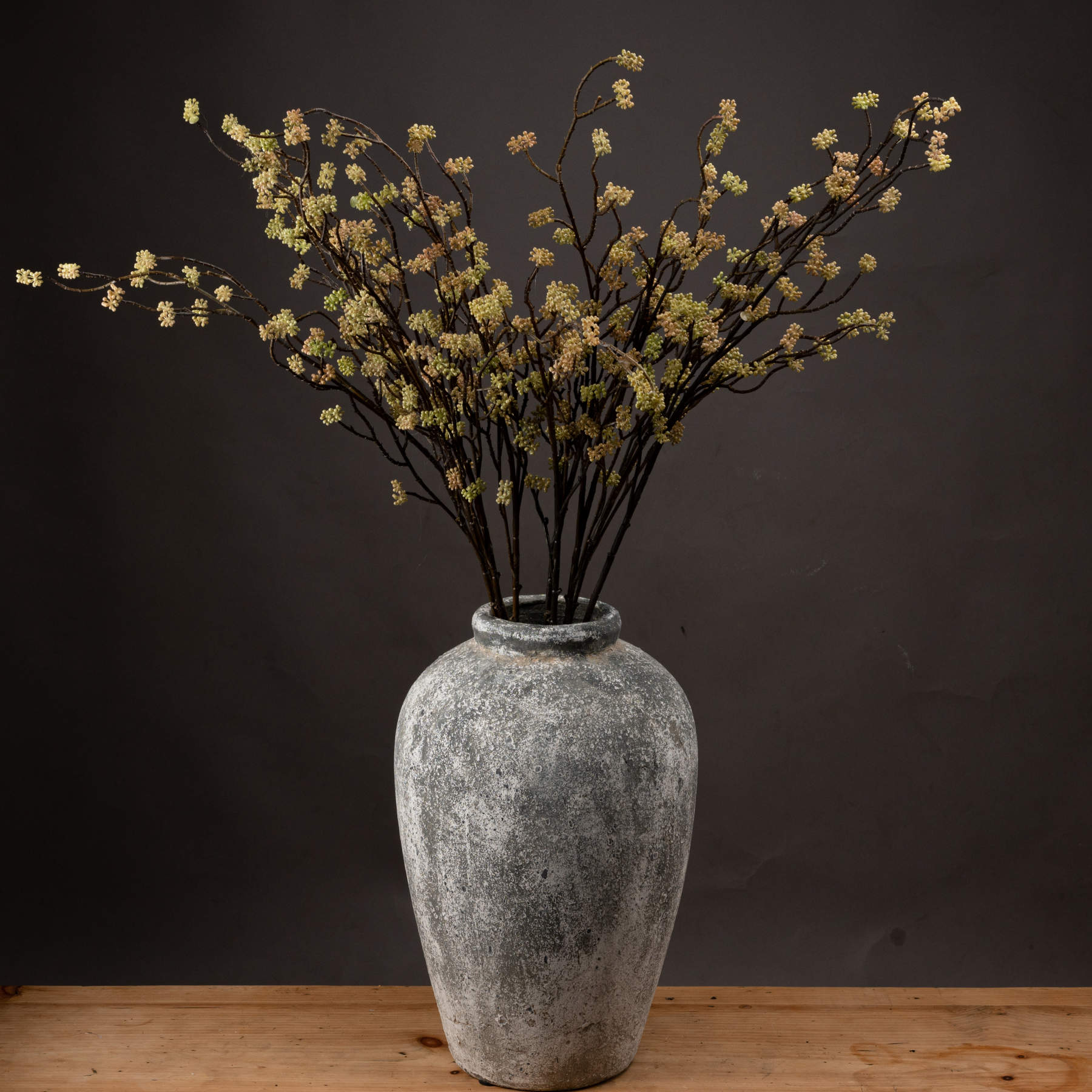 Green artificial Sedum branches in a textured gray vase, showcasing realistic details for elegant decor. Ideal for autumn styling.