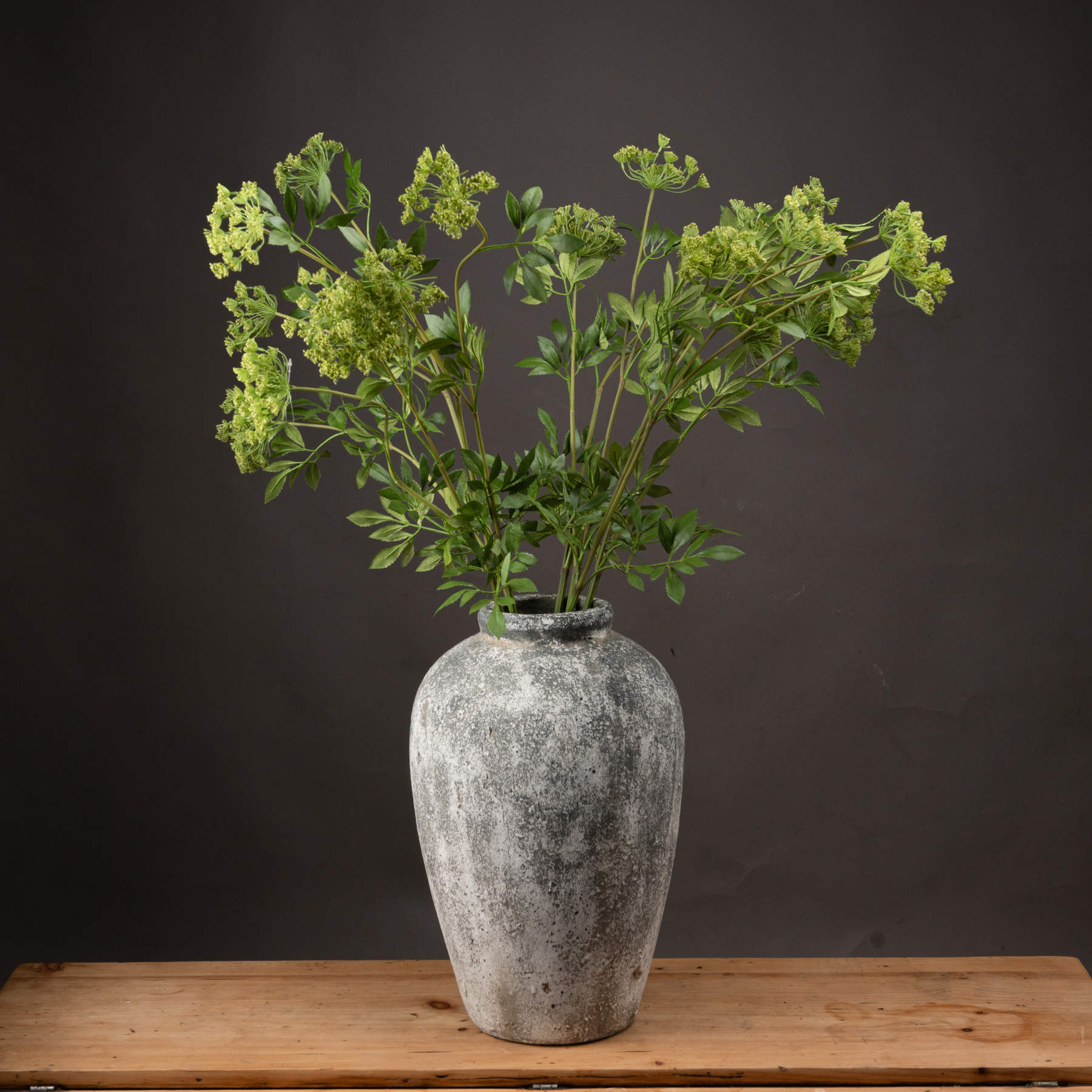 Faux cow parsley stem in a textured gray vase, featuring delicate green umbels and lush foliage for a fresh, airy look.