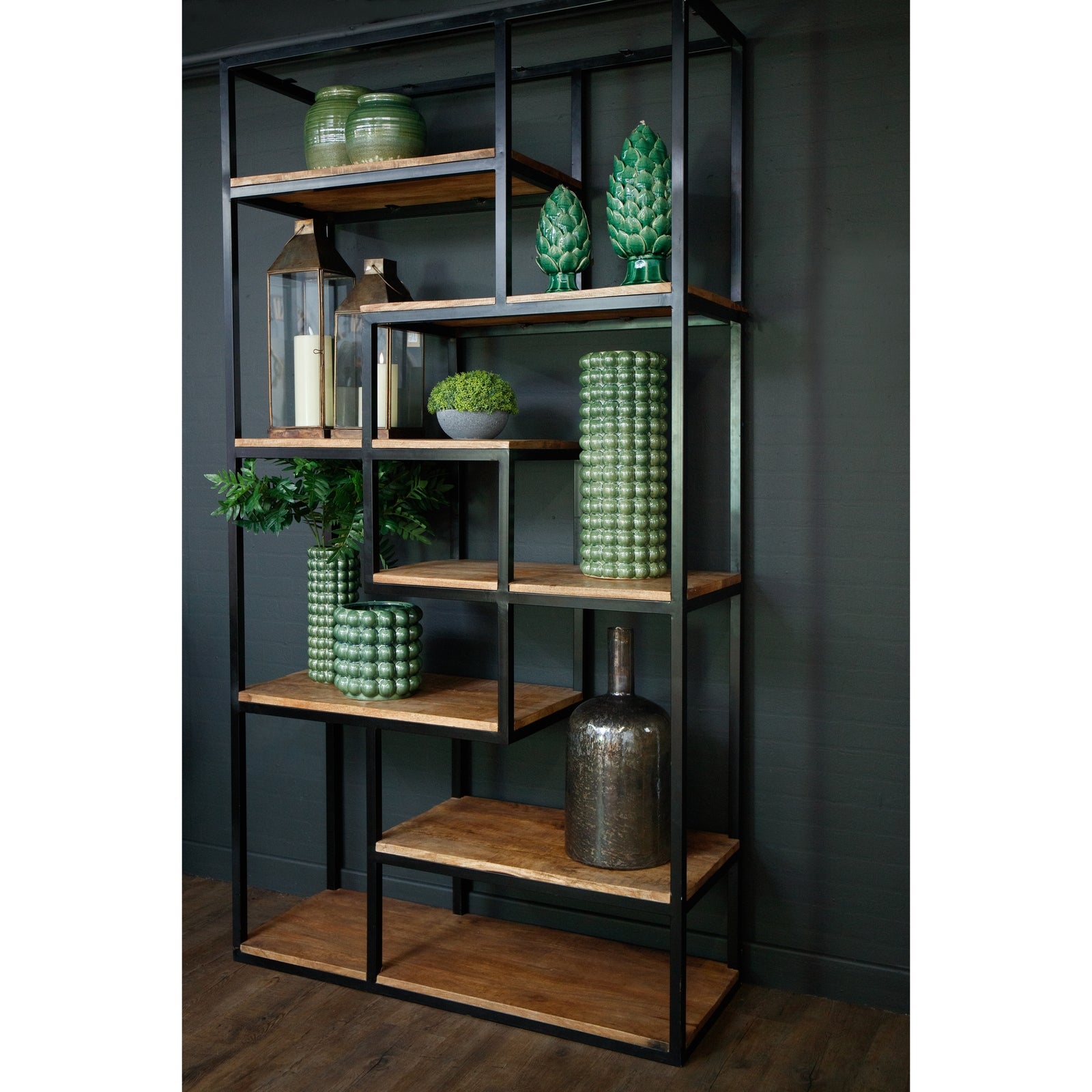 Industrial-style shelf unit featuring six wooden shelves with a black metal frame, adorned with green decorative vases and plants.
