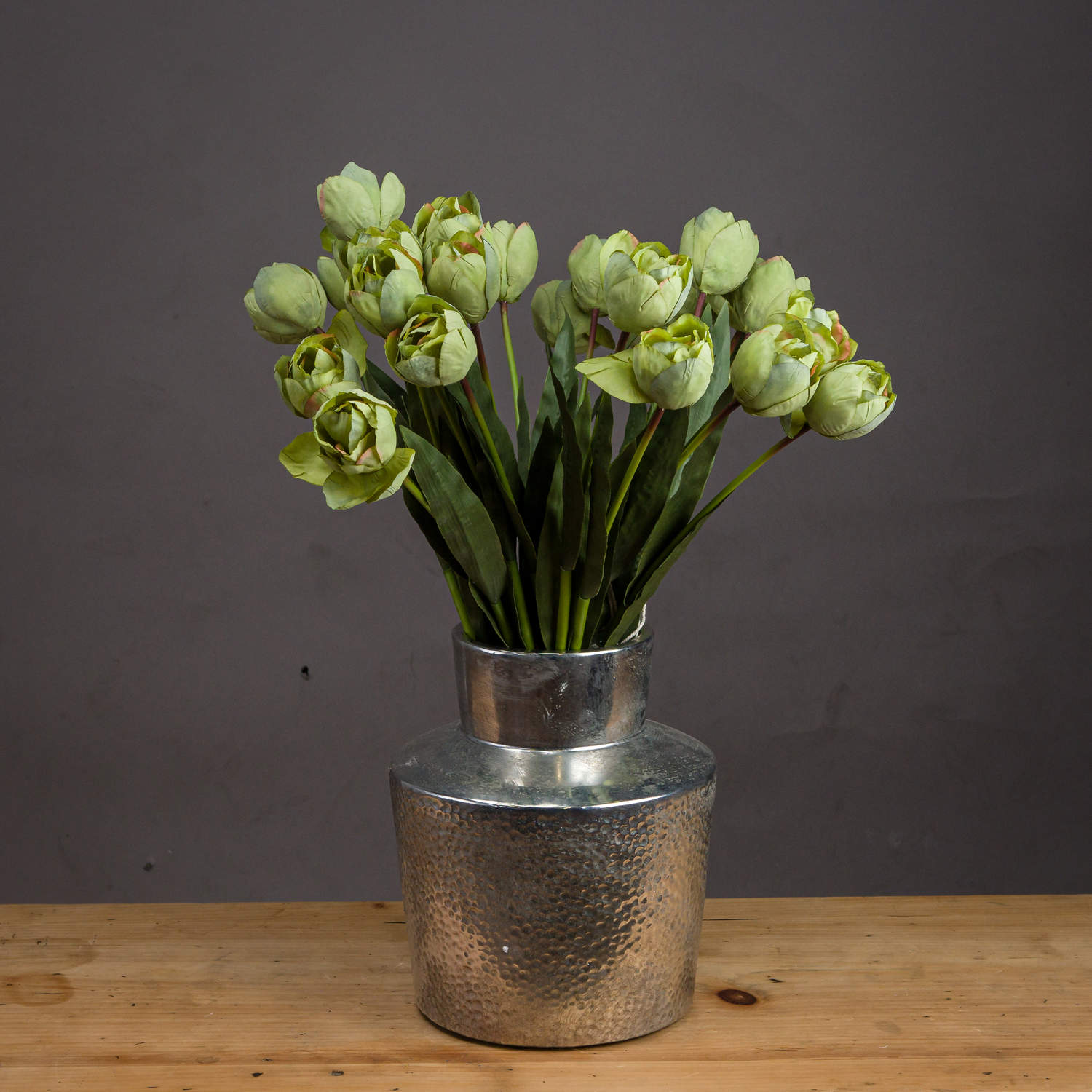 Lifelike green tulips arranged in a silver vase, showcasing realistic petals and lush leaves against a neutral backdrop.