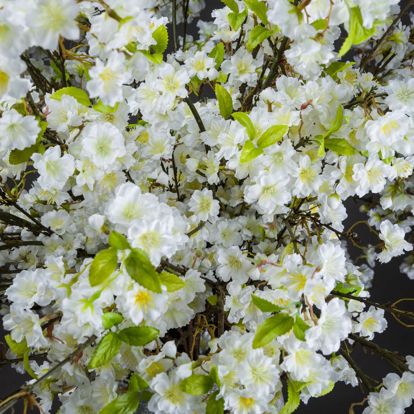 Lifelike white cherry blossoms with green leaves, creating a fresh, elegant accent suitable for any decor style.