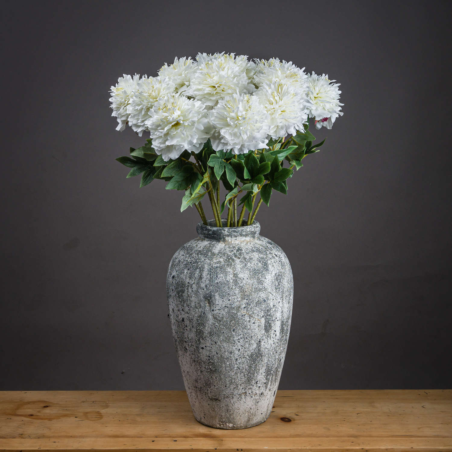 Artificial white peony bouquet in a textured gray vase, featuring detailed petals and greenery for elegant home decor.