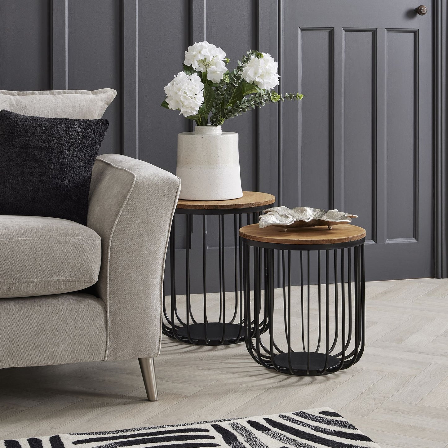 Lifelike white hydrangea stems in a textured ceramic vase on a contemporary side table, adding elegance to a cozy living space.