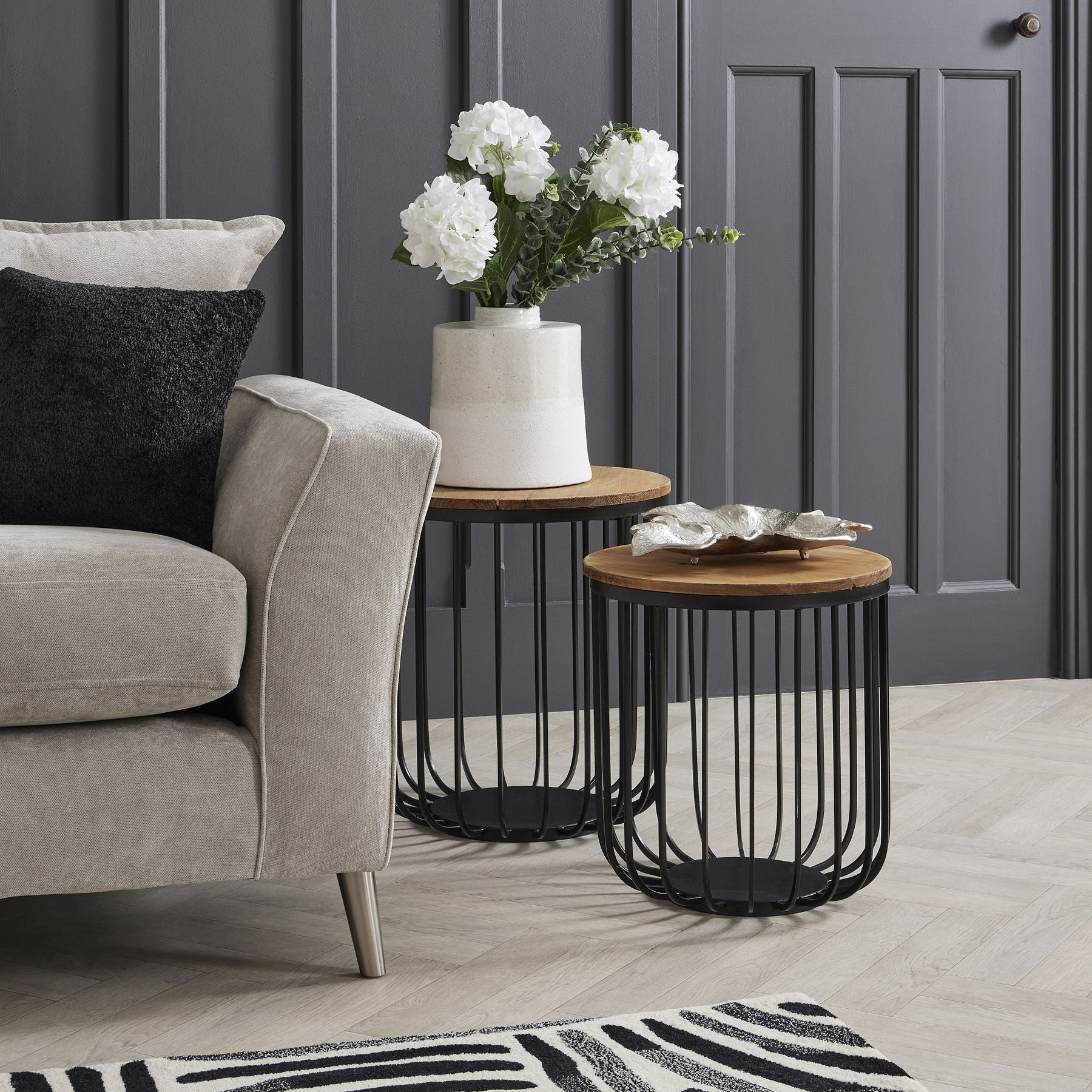Lifelike white hydrangea stems in a textured ceramic vase on a contemporary side table, adding elegance to a cozy living space.