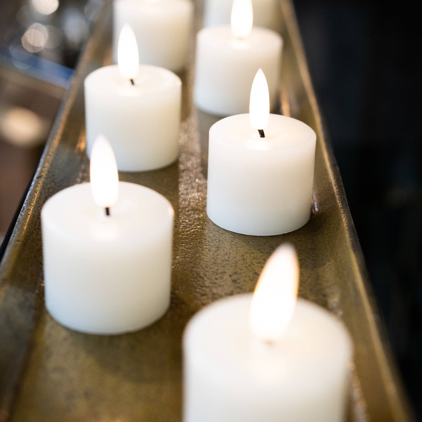 Set of six white LED tealight candles with realistic glowing flames, arranged on a metallic tray, creating a cozy ambiance.