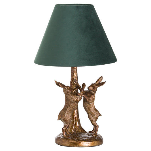 Antique gold lamp featuring sculpted hare figures, topped with an elegant green velvet shade, exuding refined charm.