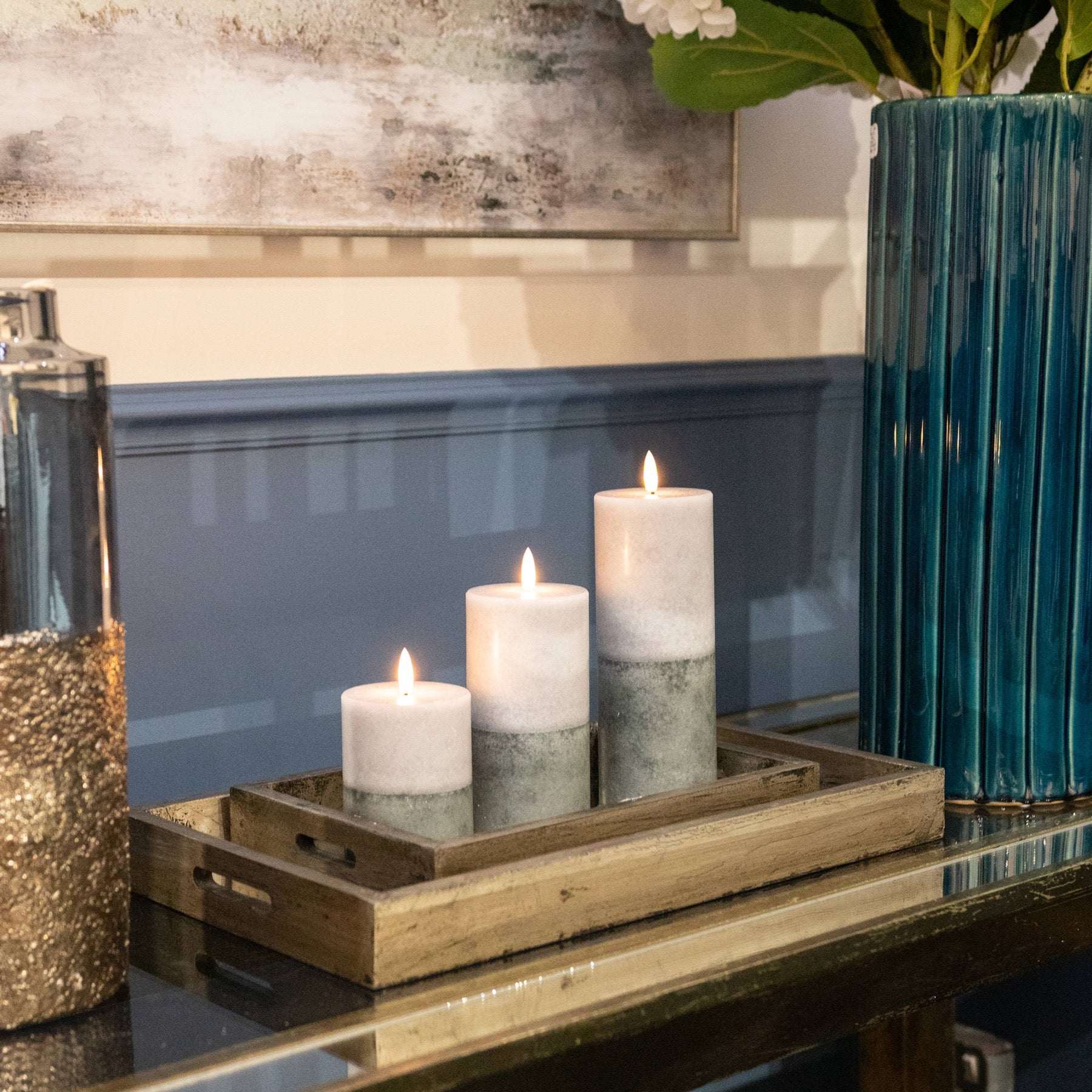 Three LED candles with a two-tone stone design sit on a wooden tray, glowing softly with warm amber light, adding elegance to the decor.