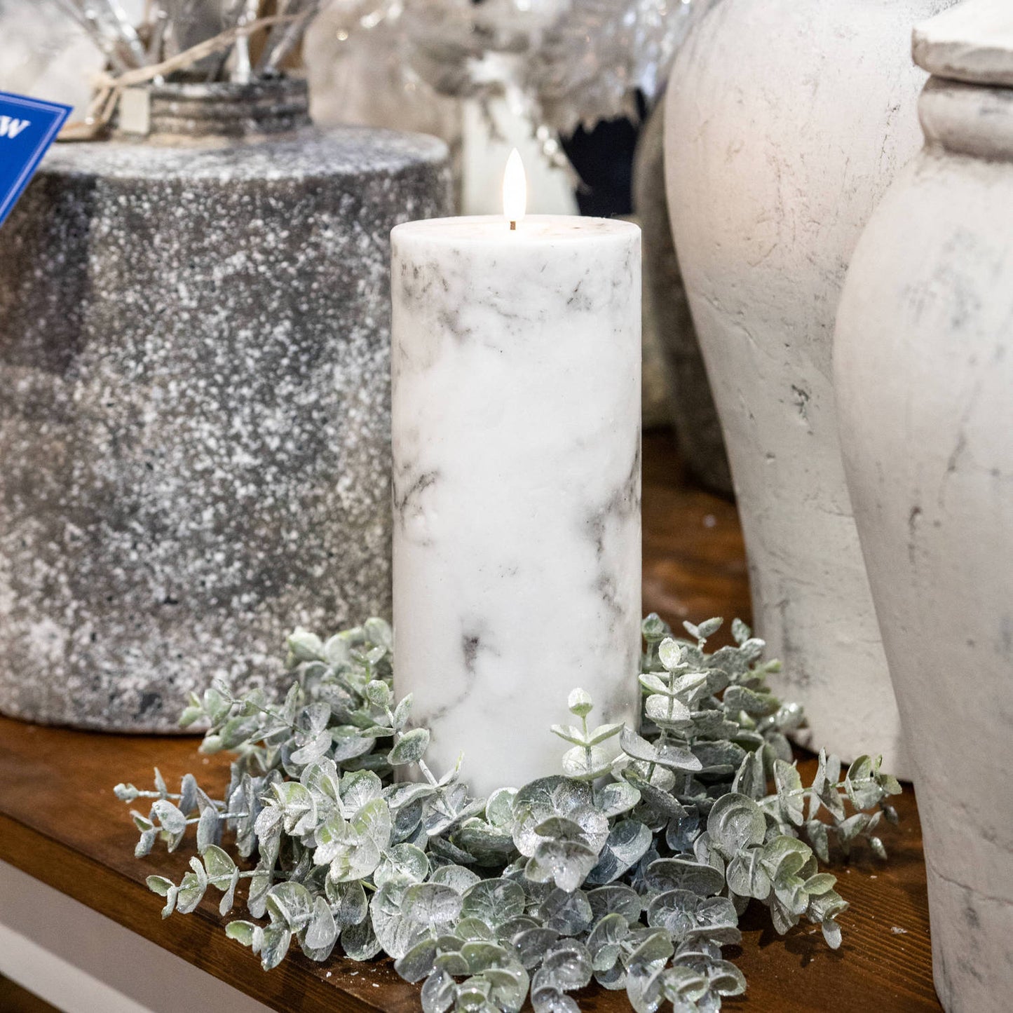 White LED candle with a marble effect, surrounded by green foliage, creating a sophisticated and inviting ambiance.