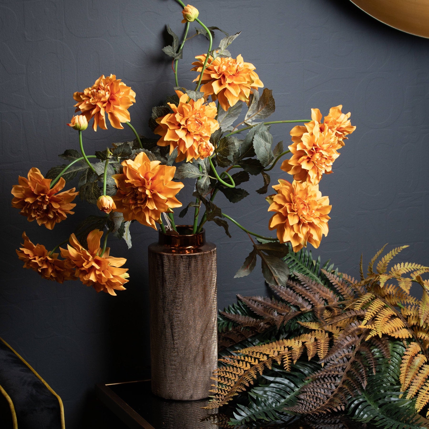 Vibrant orange dahlia stems in a modern vase, featuring intricate petal detailing against a dark background, perfect for autumn decor.